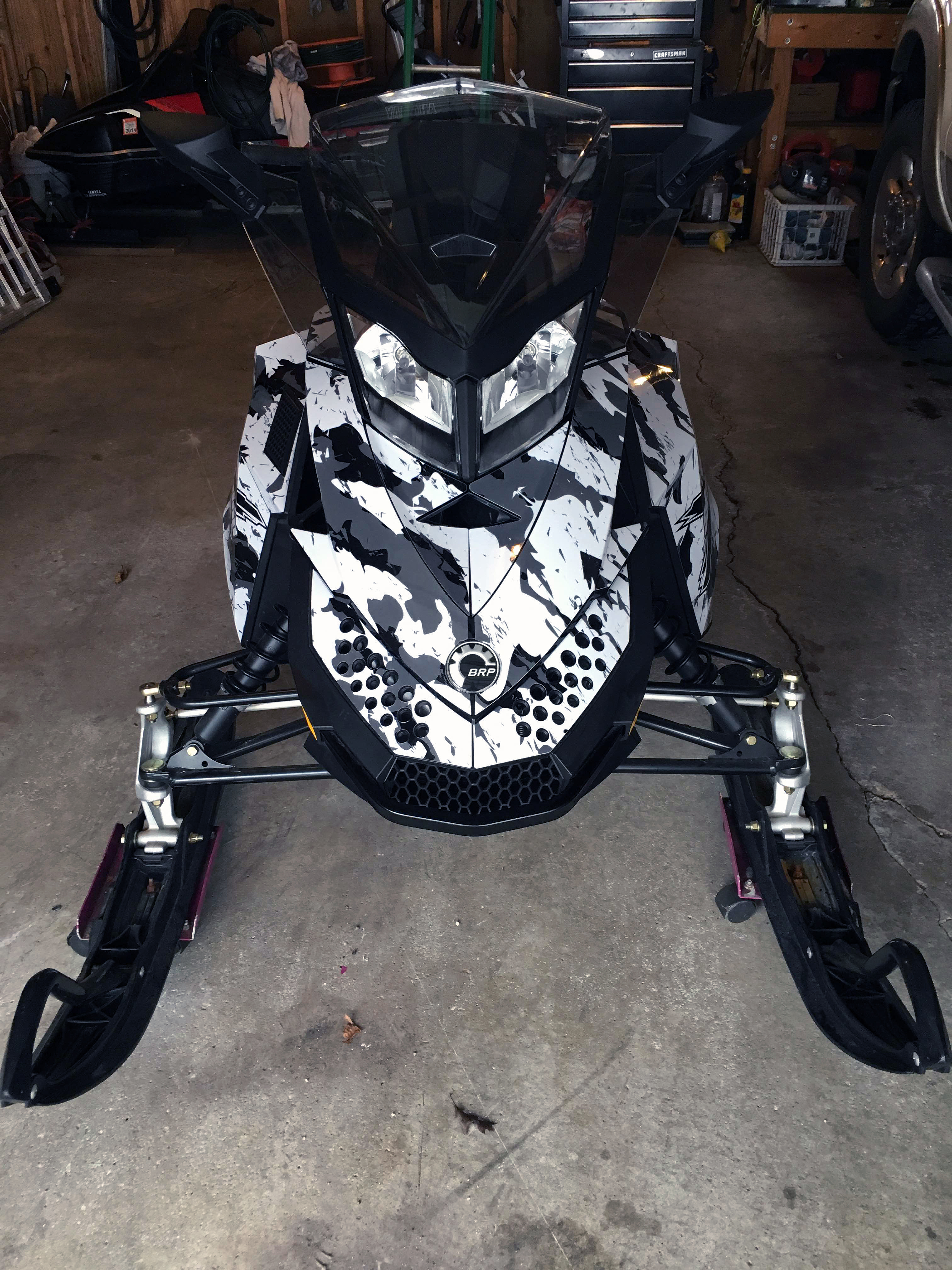 A Ski-Doo Rev XP snowmobile with a black and white Urban Camo custom vinyl wrap.