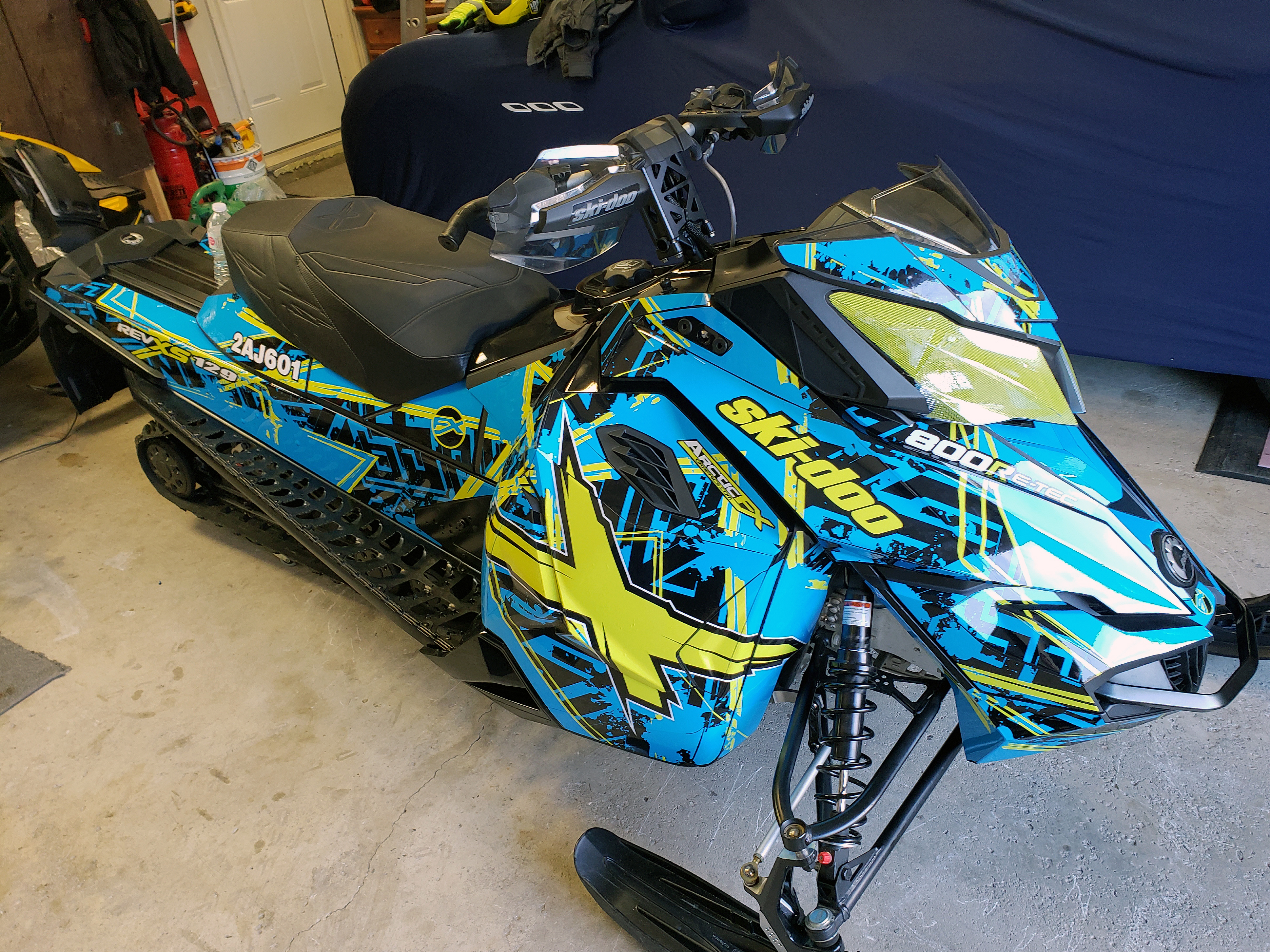 A Ski-Doo Rev XS snowmobile with a octane blue, manta, and black Havoc custom vinyl wrap.
