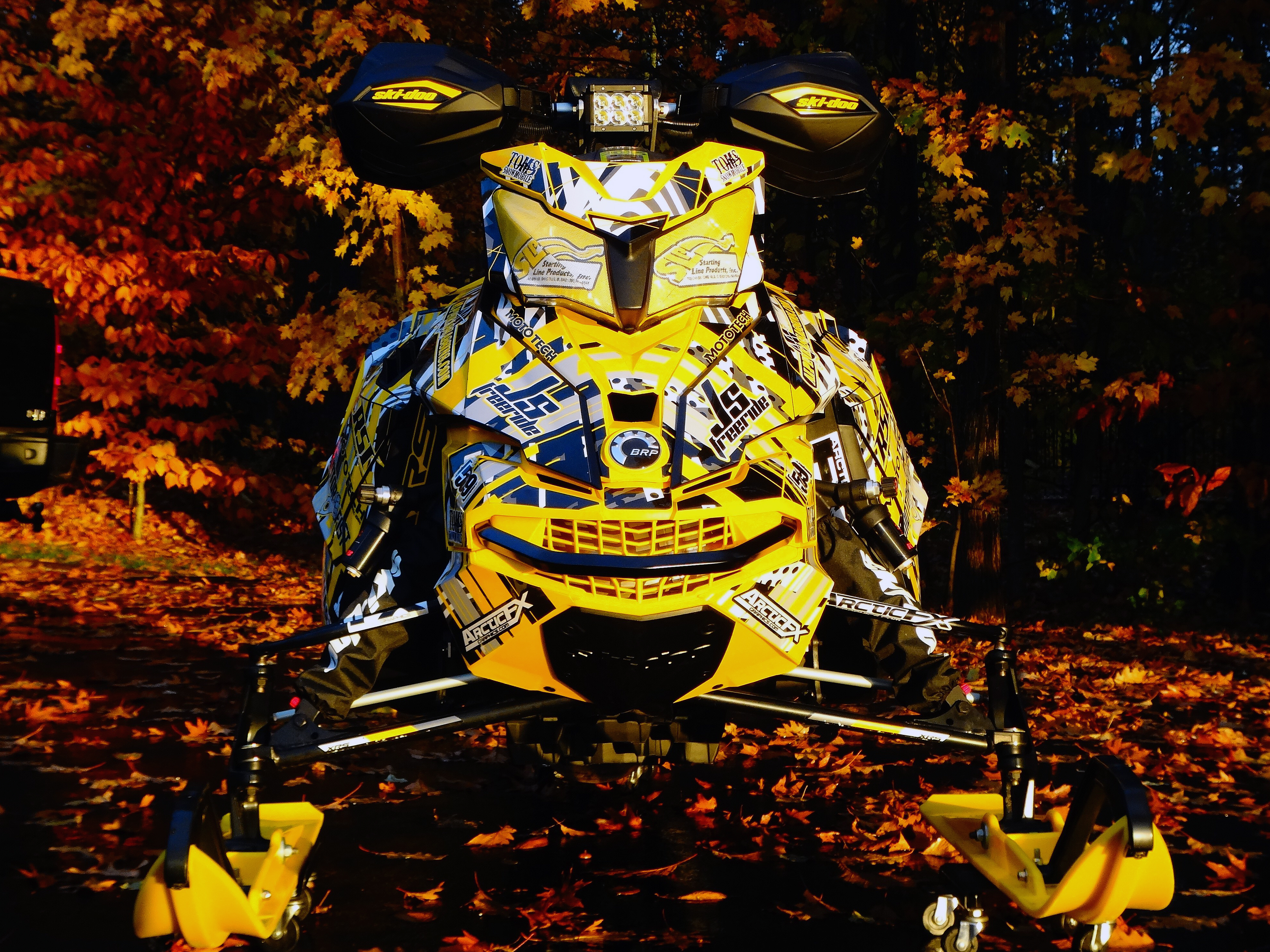A Ski-Doo Rev XS snowmobile with a yellow, black, and white Kelley Arc Reactor custom vinyl wrap.