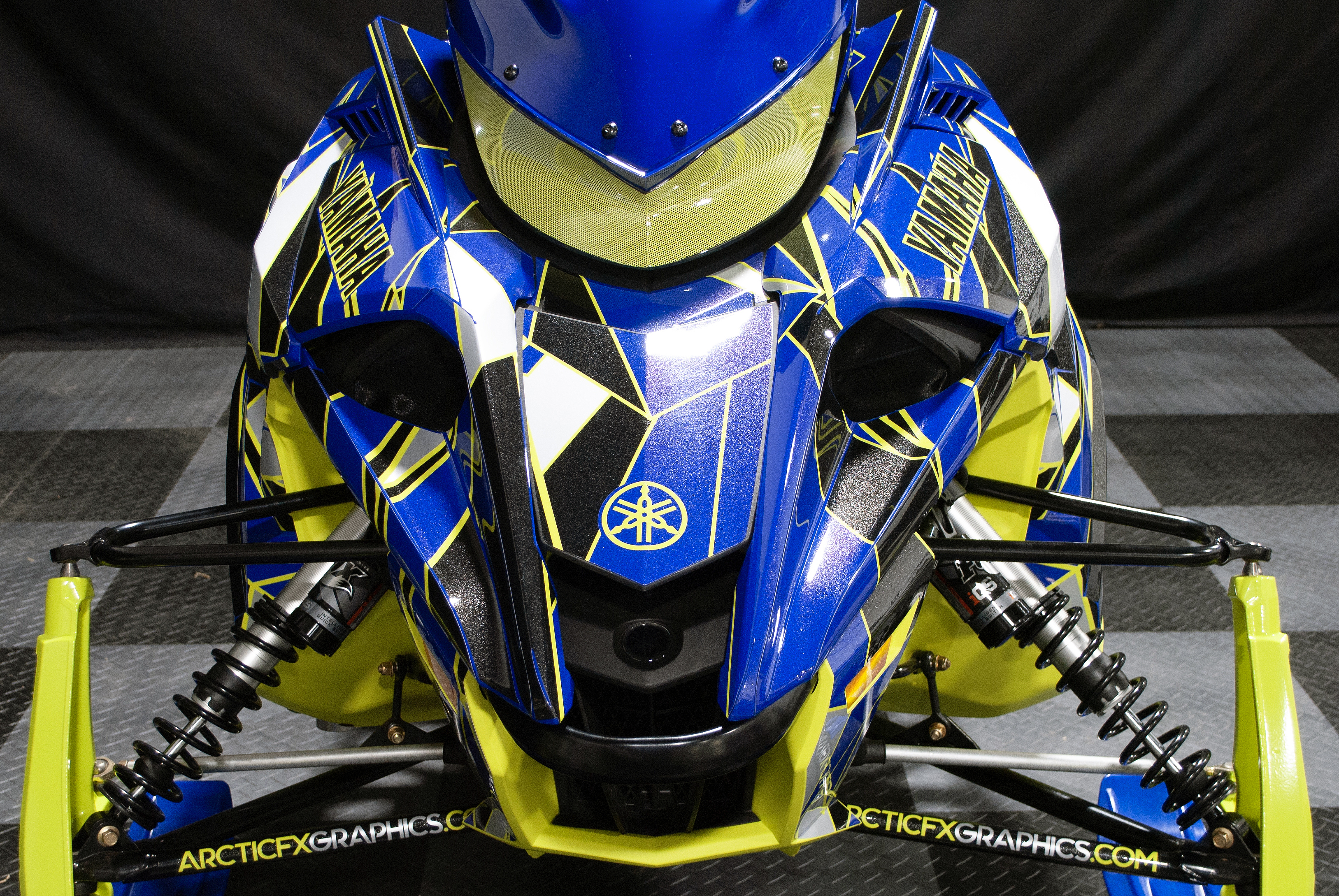 A Yamaha Sidewinder snowmobile with a blue, black, and lime squeeze Ascension custom vinyl wrap.