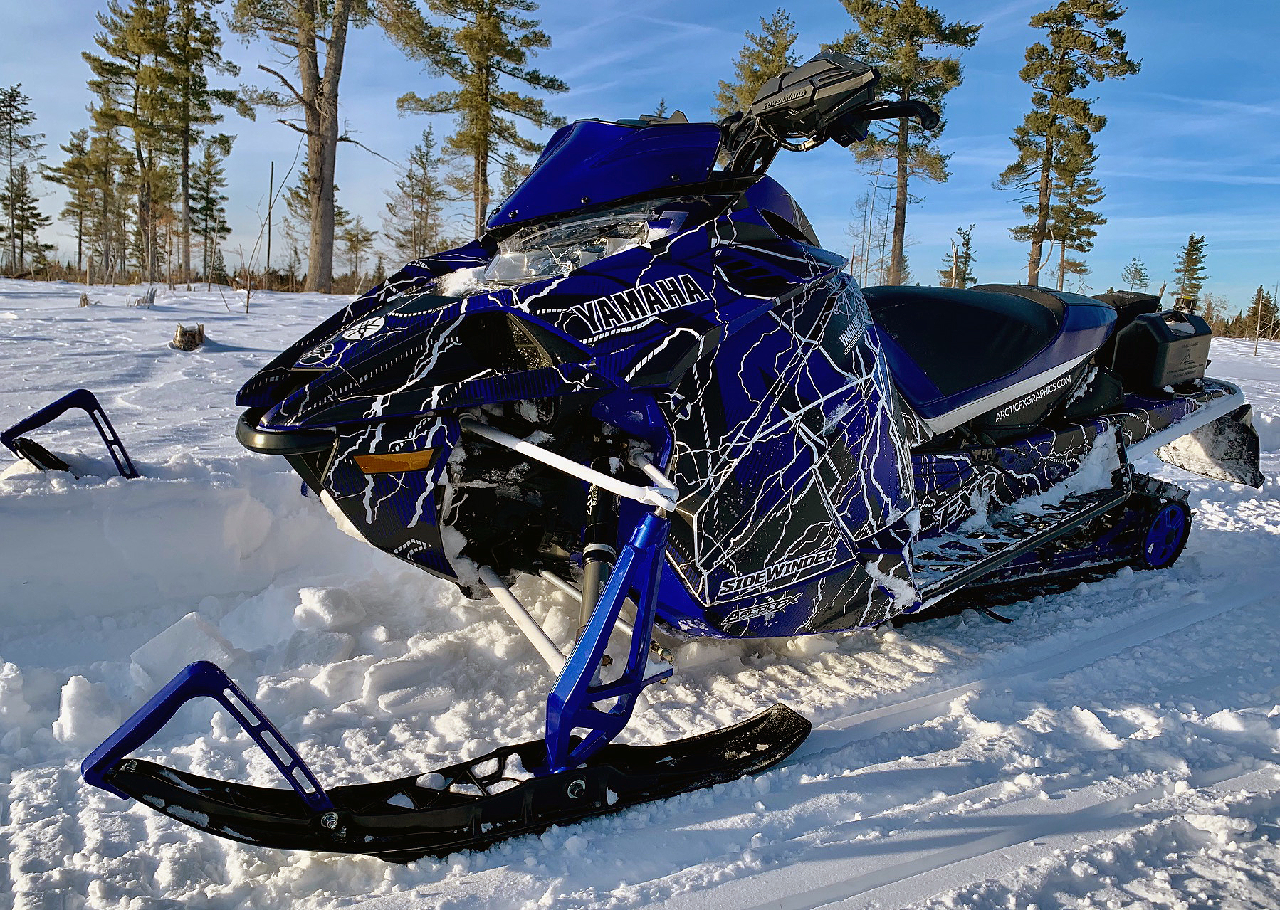 A Yamaha Sidewinder snowmobile with a blue, black, and white lightning Hard Rain custom vinyl wrap.