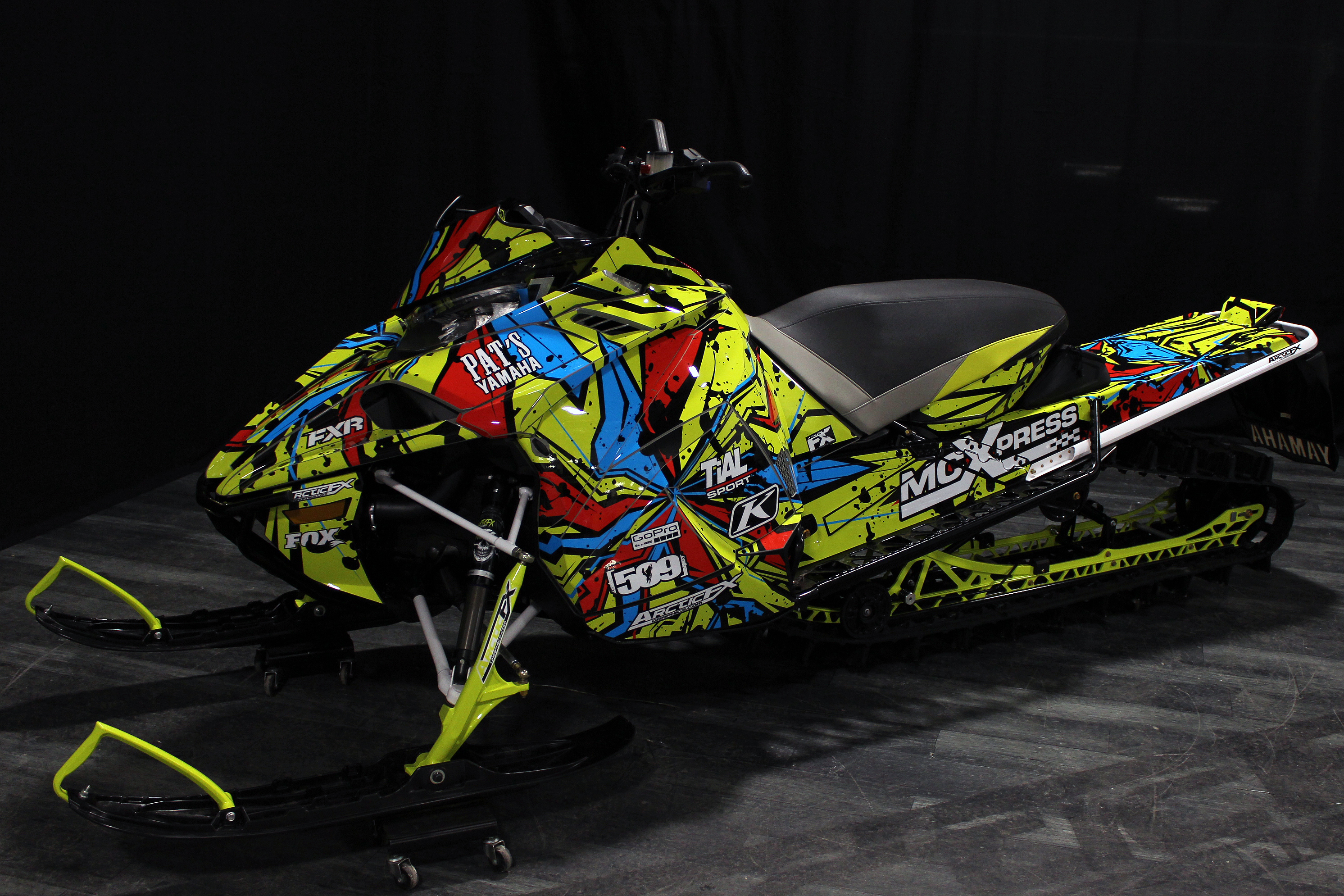 A Yamaha Sidewinder snowmobile with a lime squeeze, red, and black Stricken custom vinyl wrap.