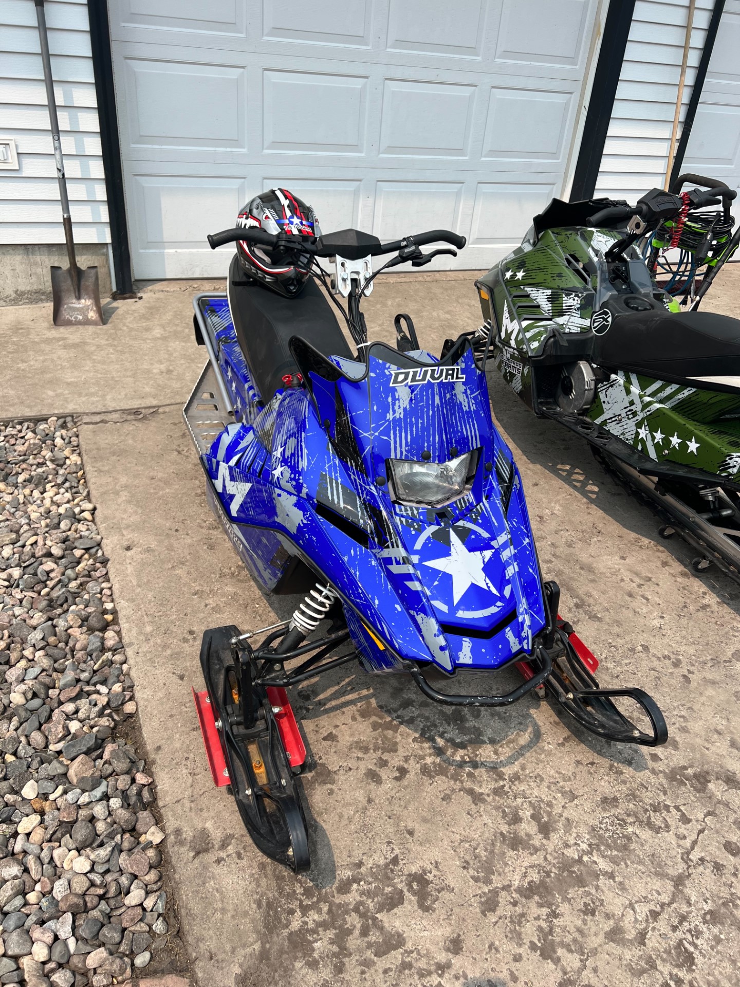 An Arctic Cat ZR200 youth snowmobile with a blue and green Wartorn custom vinyl wrap.