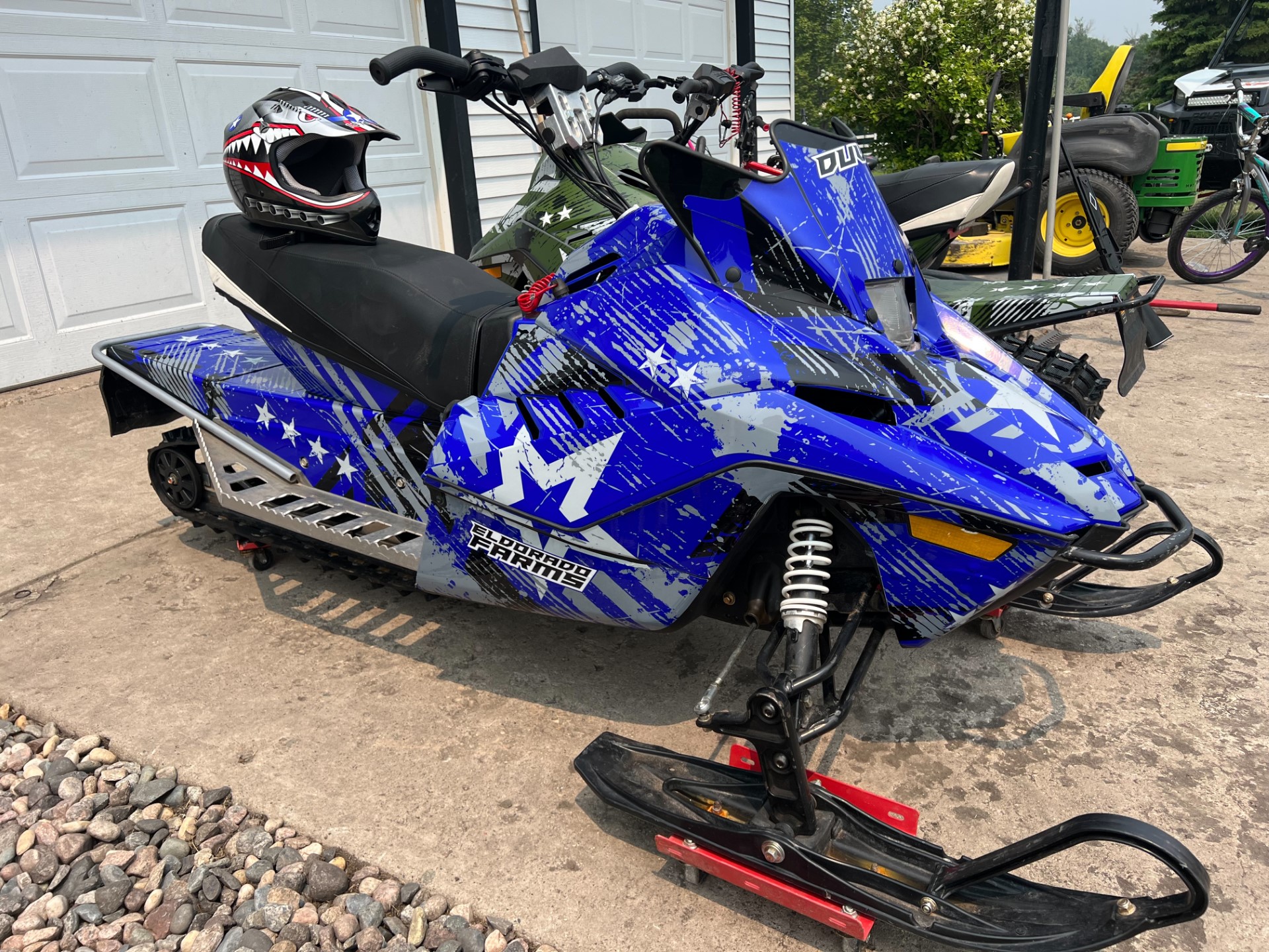 An Arctic Cat ZR200 youth snowmobile with a blue and green Wartorn custom vinyl wrap.