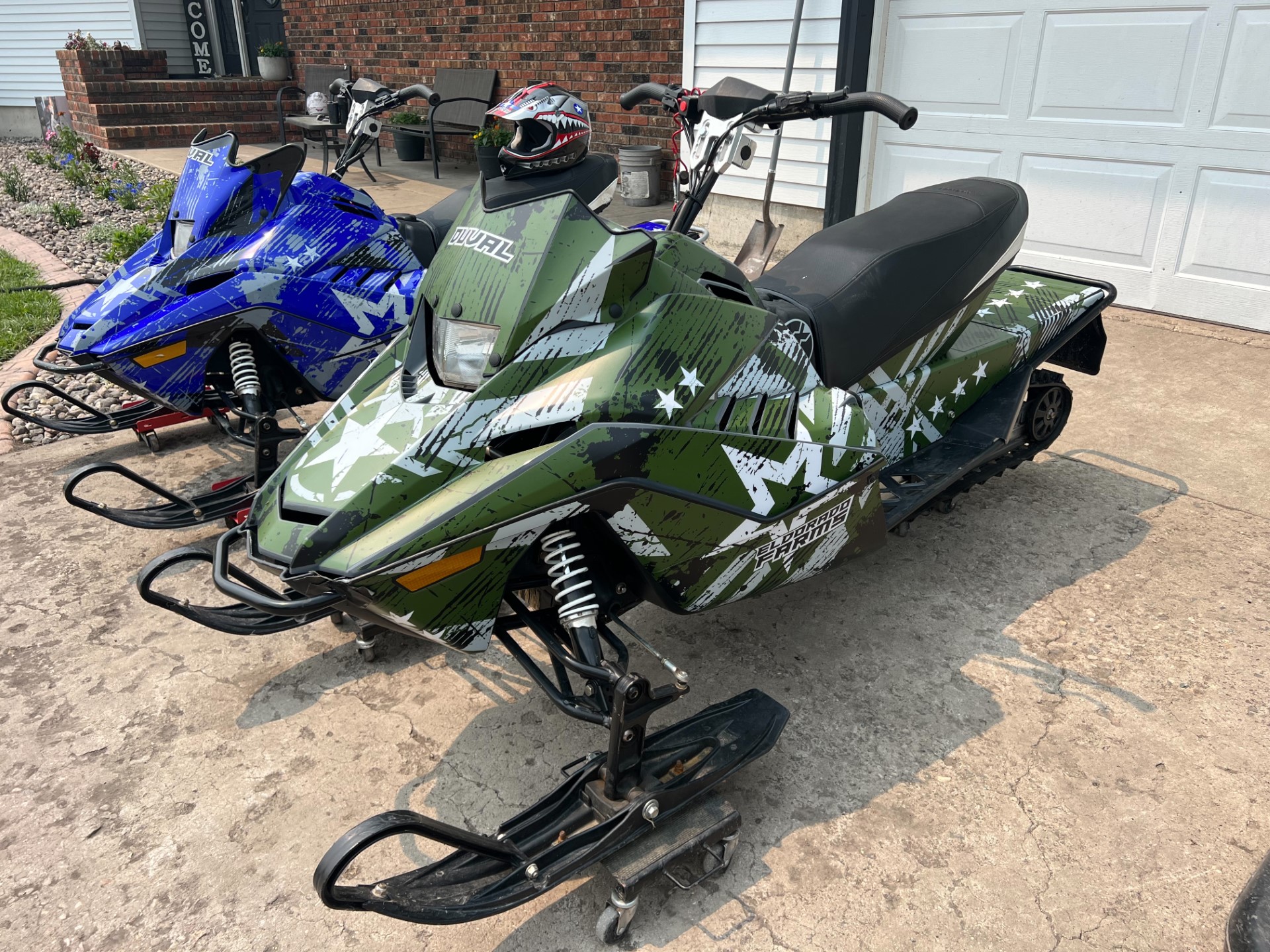 An Arctic Cat ZR200 youth snowmobile with a blue and green Wartorn custom vinyl wrap.