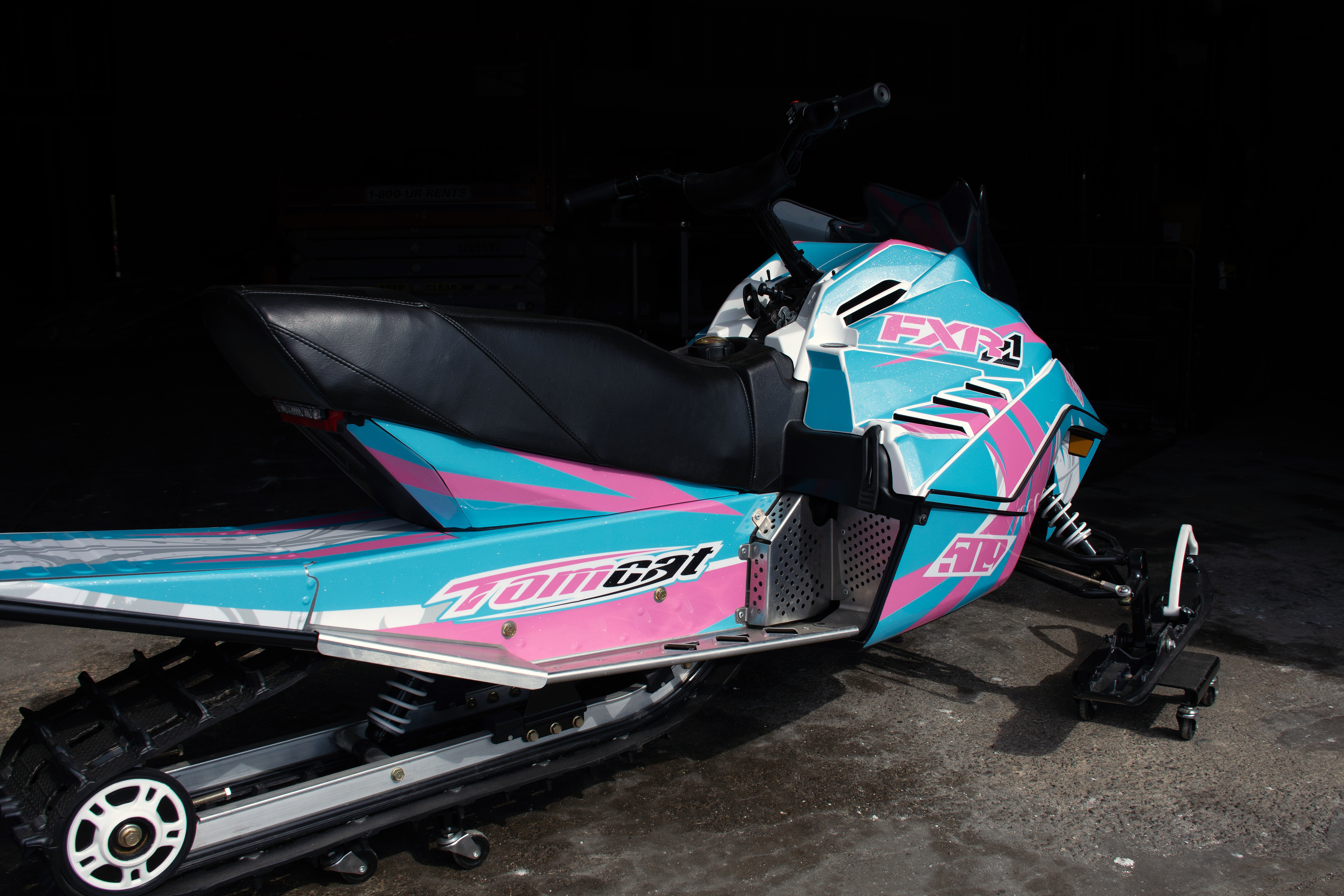 A Yamaha SnoScoot youth snowmobile with a white, pink, and blue Surge custom vinyl wrap.