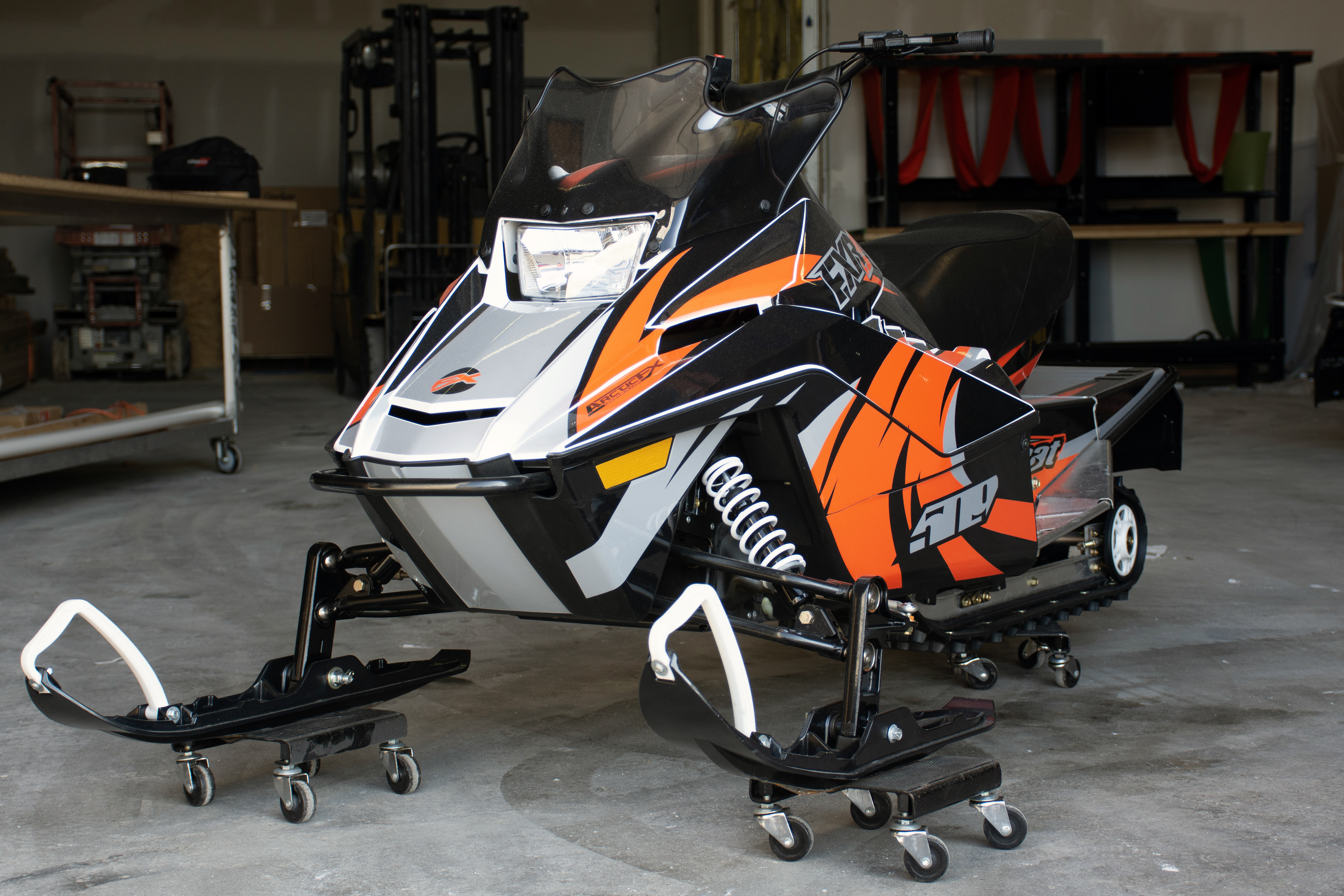 A Yamaha SnoScoot youth snowmobile with a orange, black, and gray Surge custom vinyl wrap.