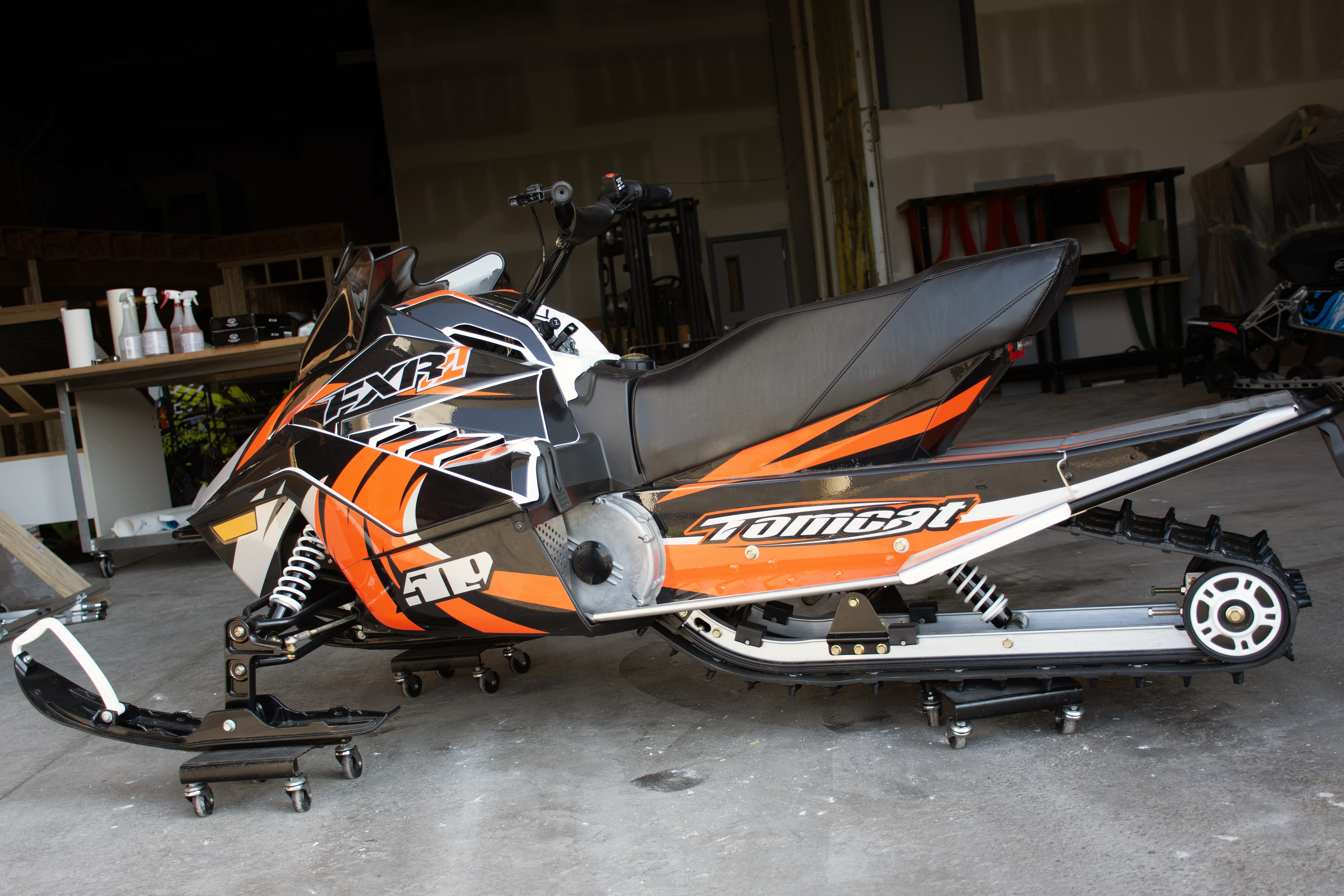 A Yamaha SnoScoot youth snowmobile with a orange, black, and gray Surge custom vinyl wrap.