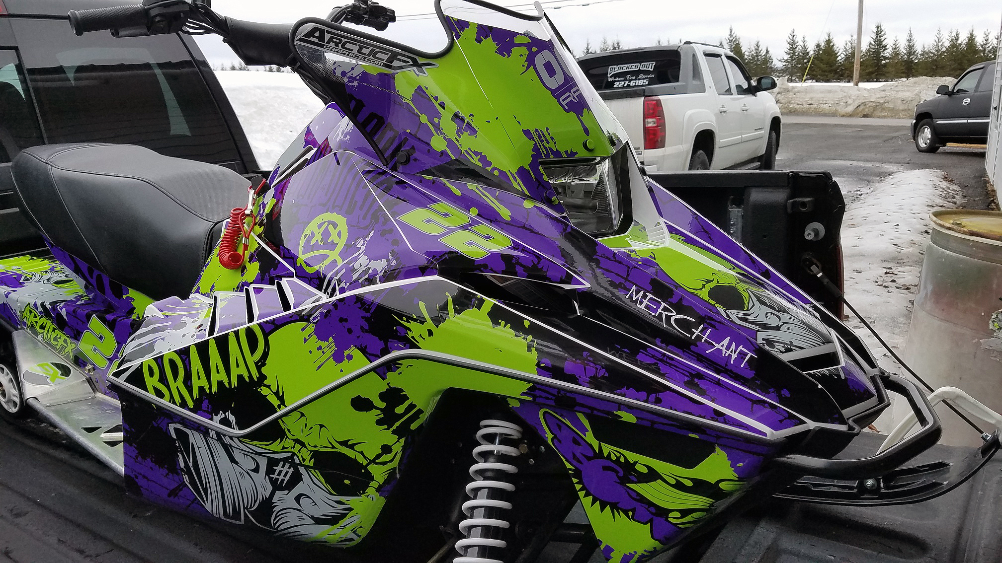 A Yamaha SnoScoot youth snowmobile with a purple, black, and lime Tagged custom vinyl wrap.
