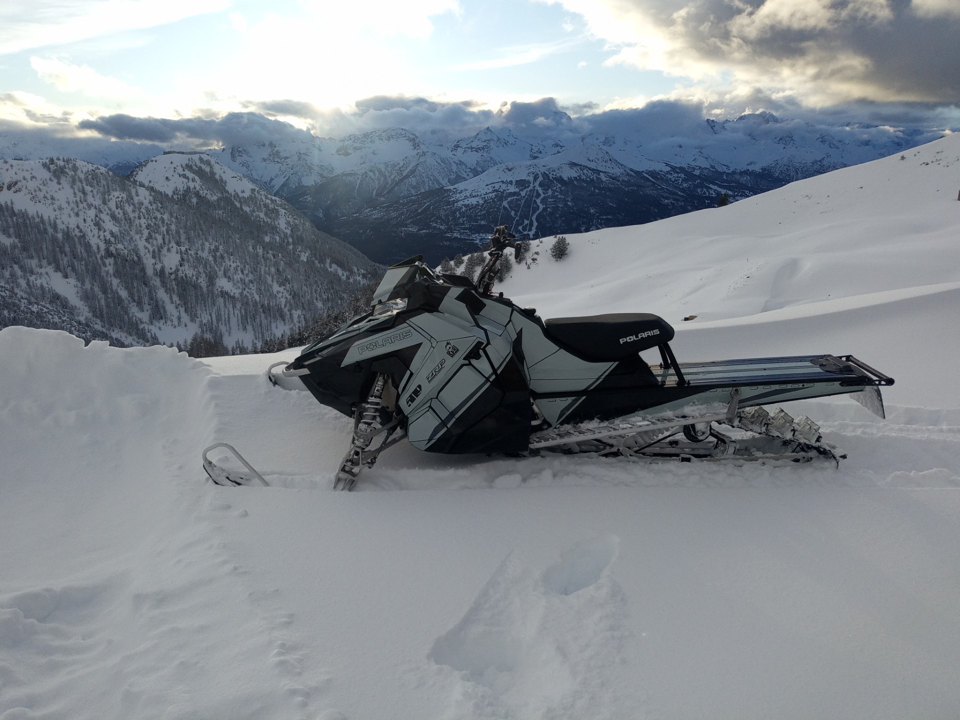 A Polaris Axys Mountain snowmobile with a light gray, black, gunmetal gray, and asphalt gray Turcotte Syndicate custom vinyl wrap.