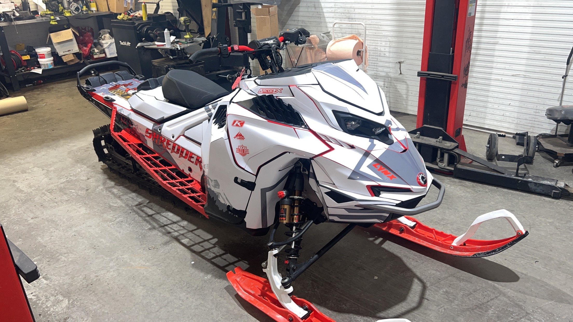A Lynx snowmobile with a white, charcoal gray, monument gray, light gray, and black Ponsor Splice custom vinyl wrap.