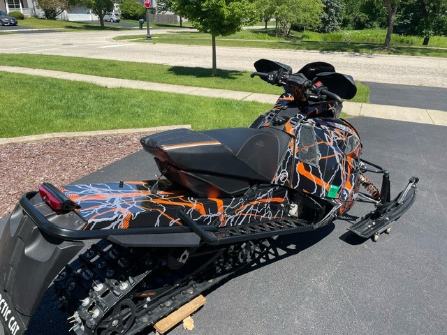 An ArcticCat Next-Gen snowmobile with a black, strike orange, and charcoal gray Hard Rain custom vinyl wrap.