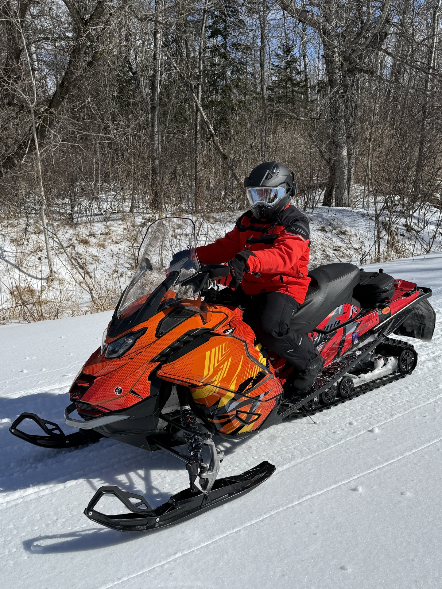 A Ski-Doo Gen5 Trail snowmobile with a white, black, red, gray, orange, and yellow Compound custom vinyl wrap.