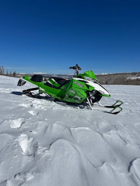An ArcticCat Proclimb snowmobile with a white, black, and electric green Andy Thomas Peaked custom vinyl wrap.