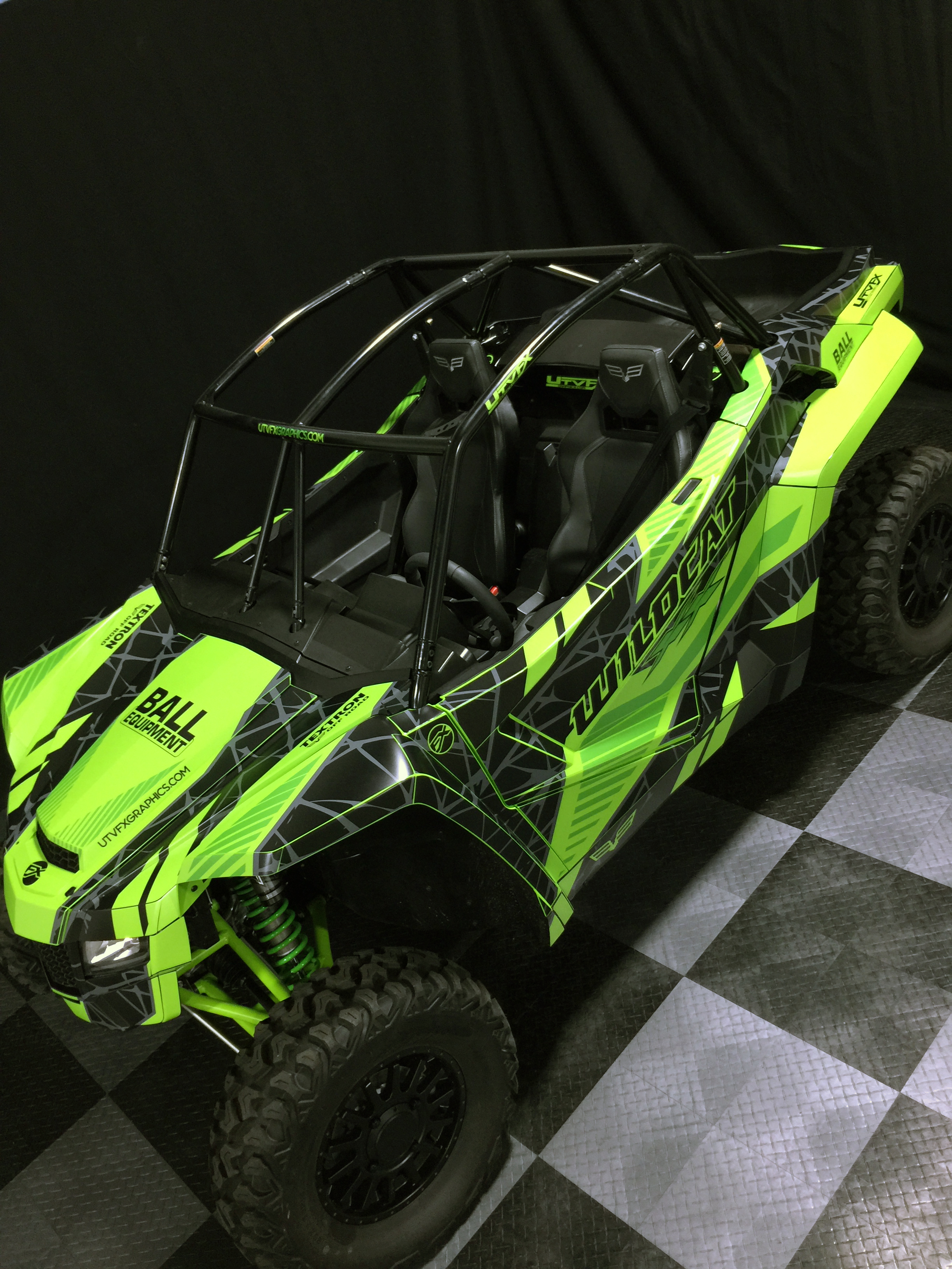 A Arctic Cat Wildcat XX side-by-side with a green, black, and dark gray Fractal custom vinyl wrap.