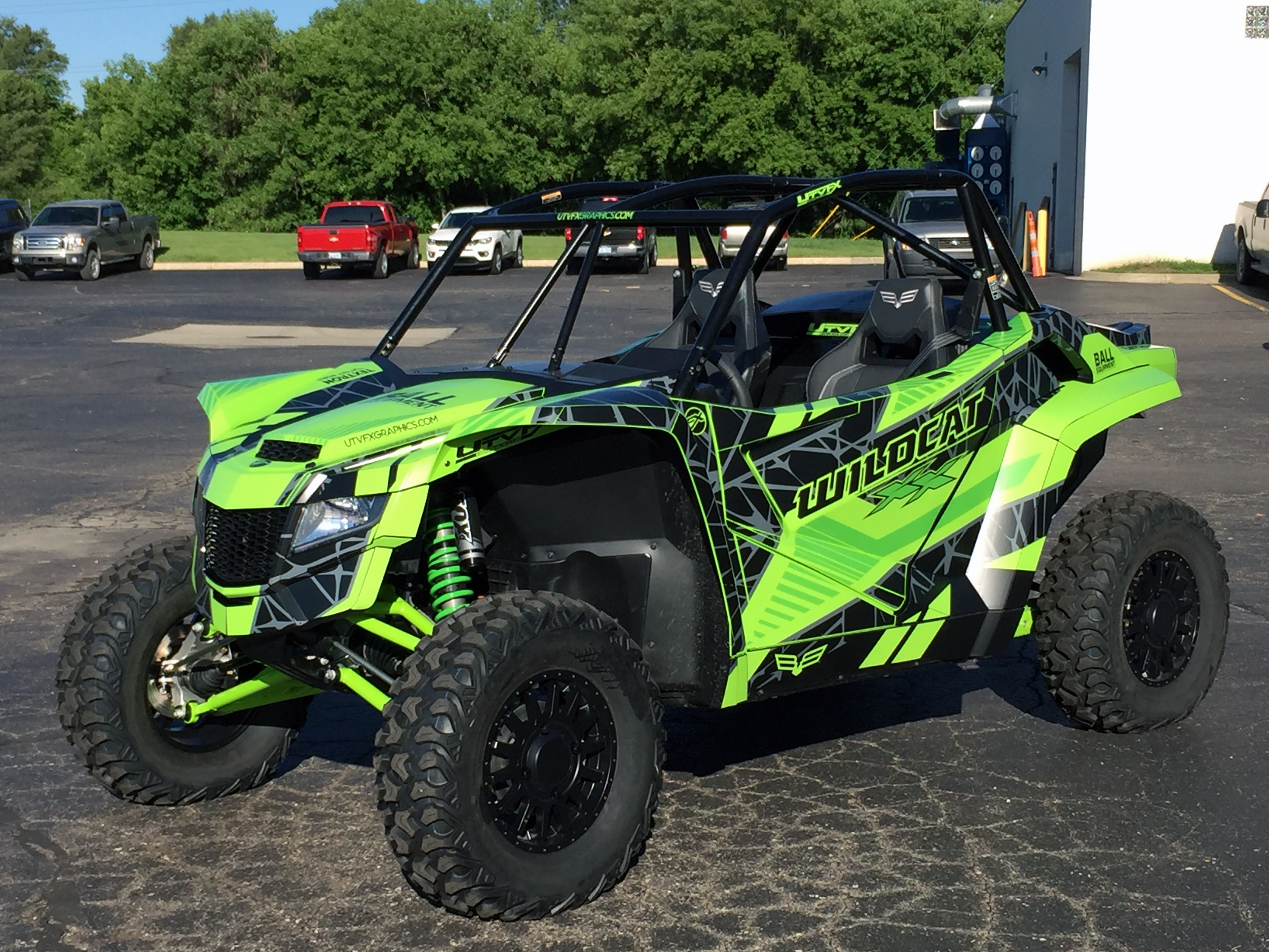 A Arctic Cat Wildcat XX side-by-side with a green, black, and dark gray Fractal custom vinyl wrap.