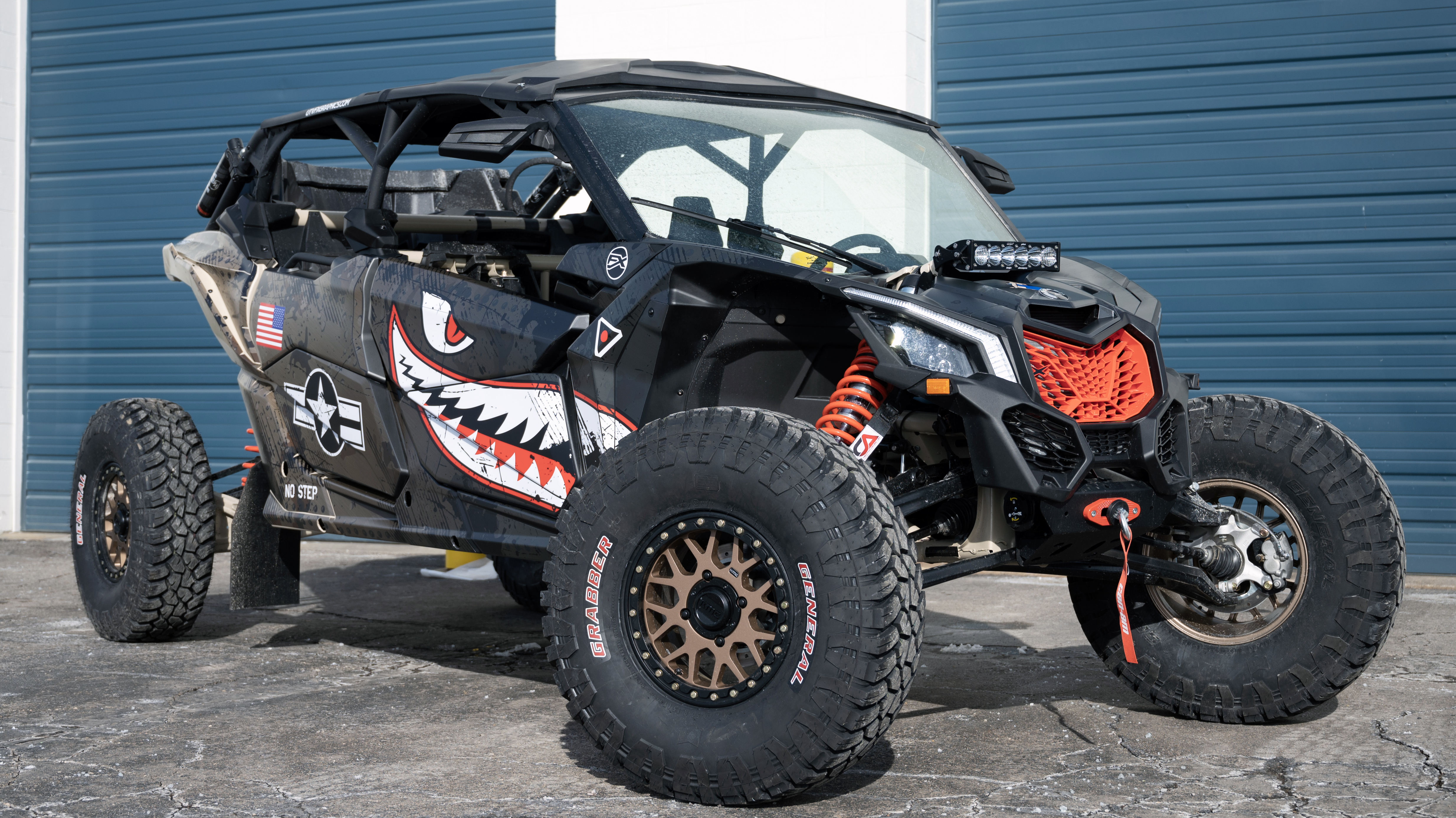 A Can-Am Maverick X3 Max side-by-side with a black, tan, and red tiger shark plane custom vinyl wrap.