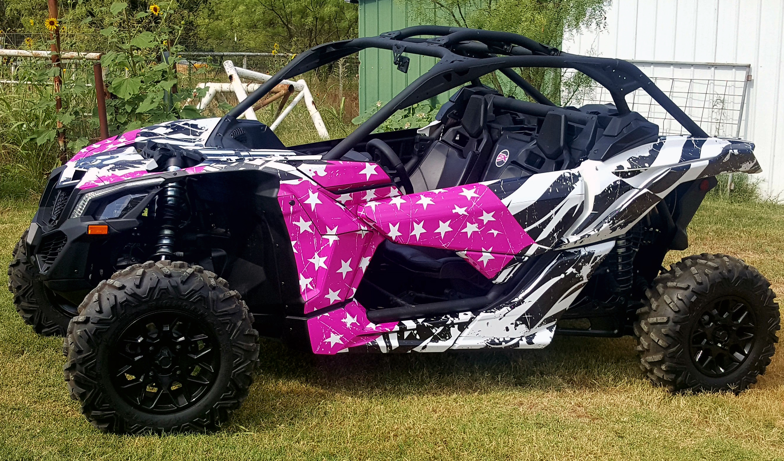 A Can-Am Maverick X3 side-by-side with a pink, white, and black grunge American Flag custom vinyl wrap.