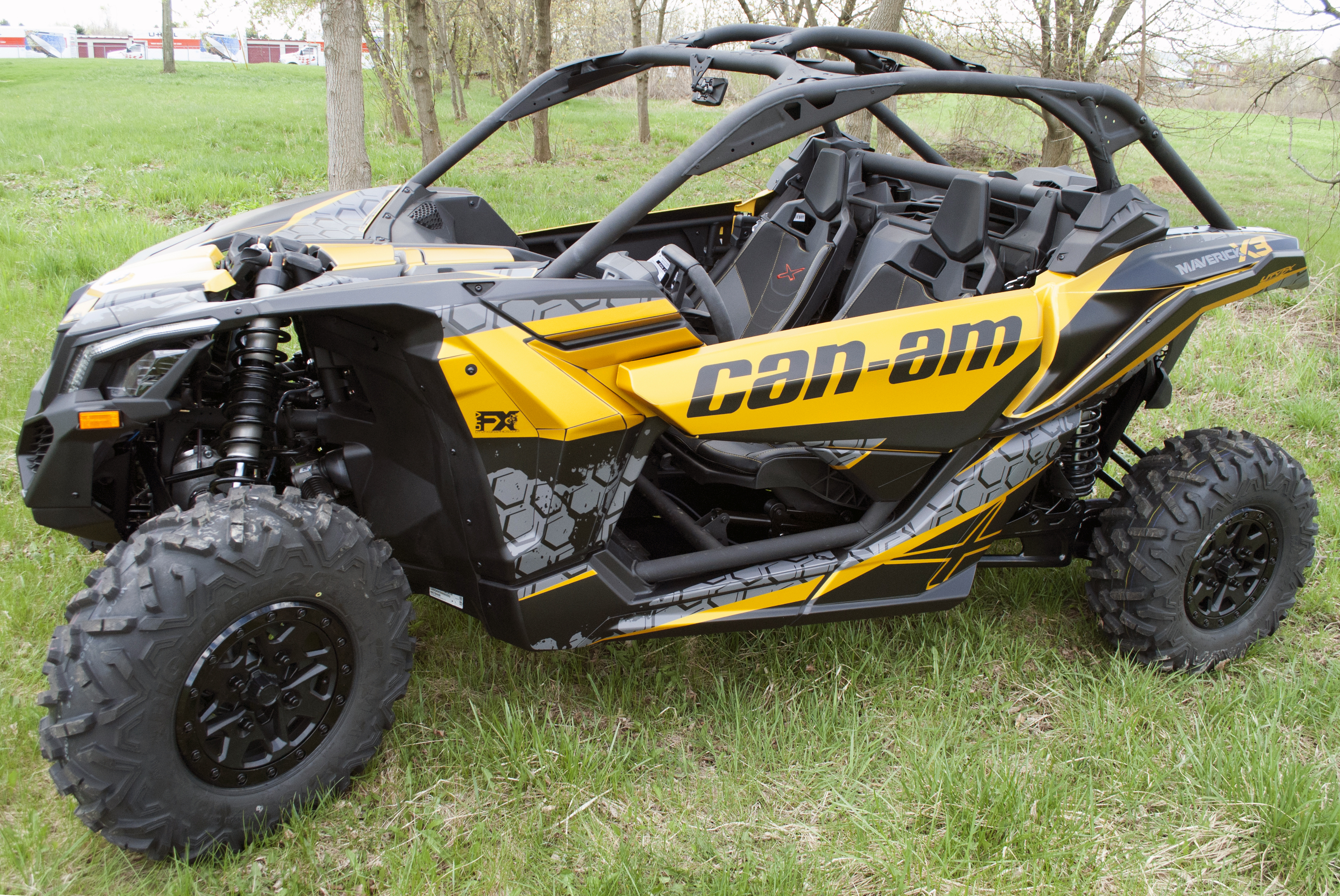 A Can-Am Maverick X3 side-by-side with a yellow, black, and dark gray honeycomb Paradigm custom vinyl wrap.