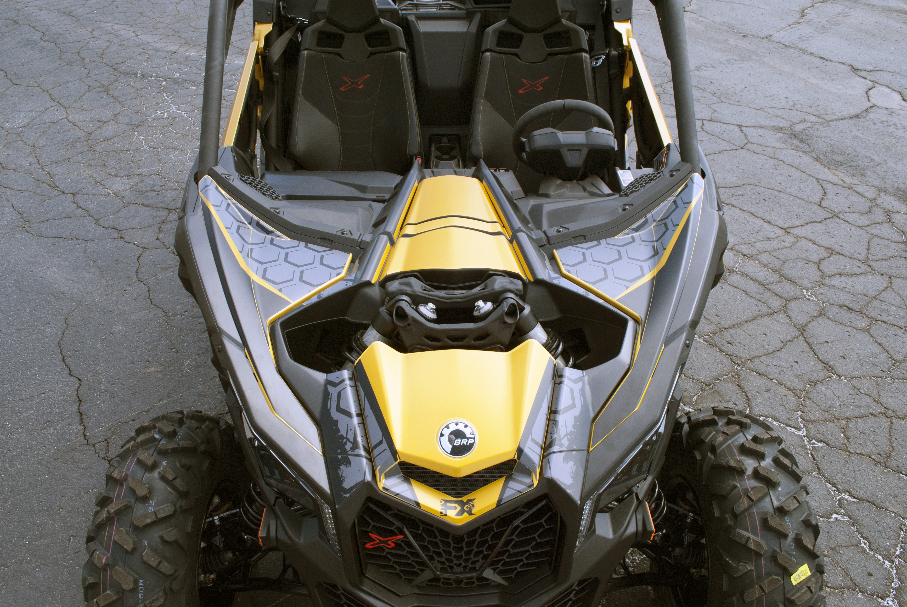 A Can-Am Maverick X3 side-by-side with a yellow, black, and dark gray honeycomb Paradigm custom vinyl wrap.