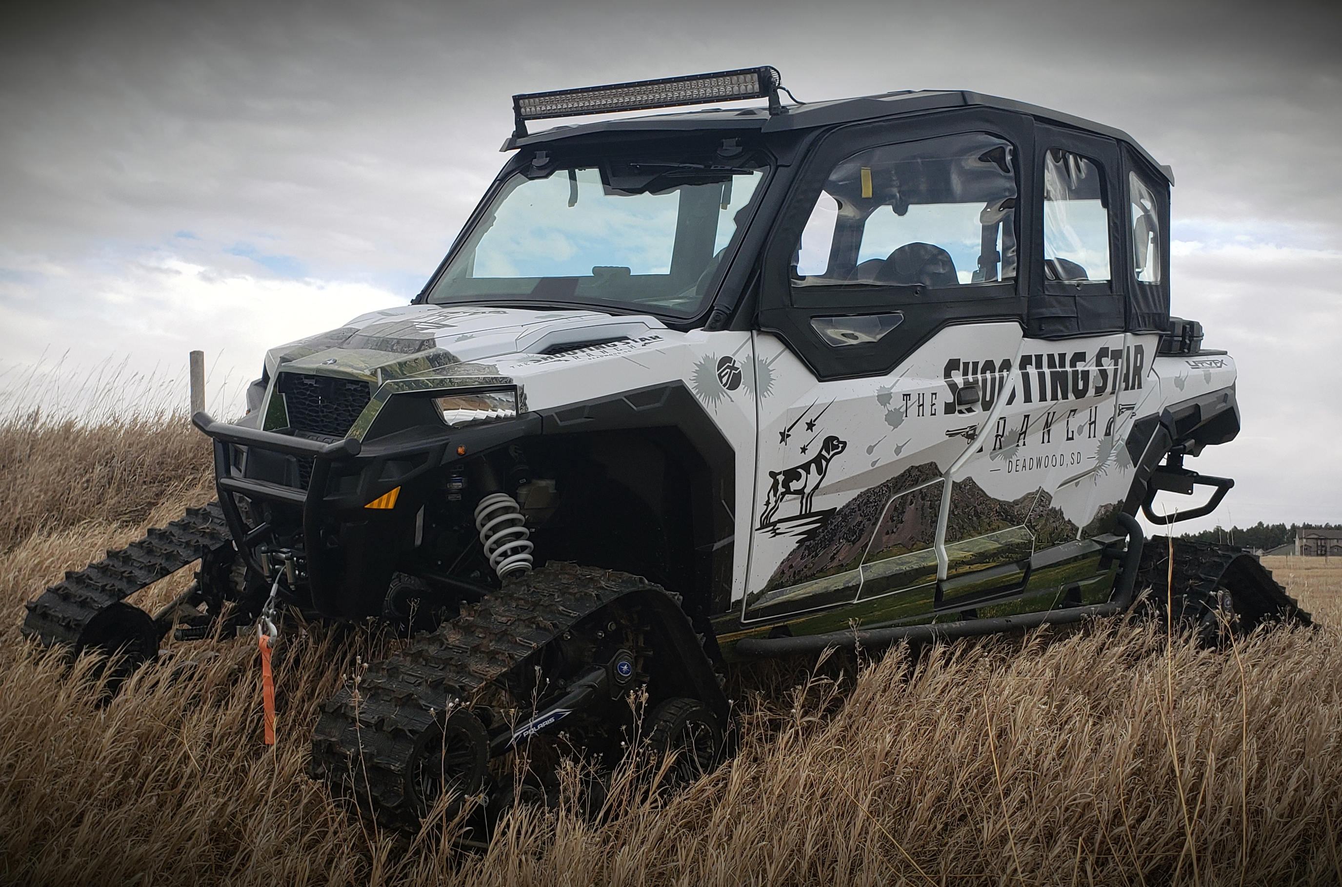 A Polaris General 4 Door side-by-side with a white, black and green shooting star custom vinyl wrap.