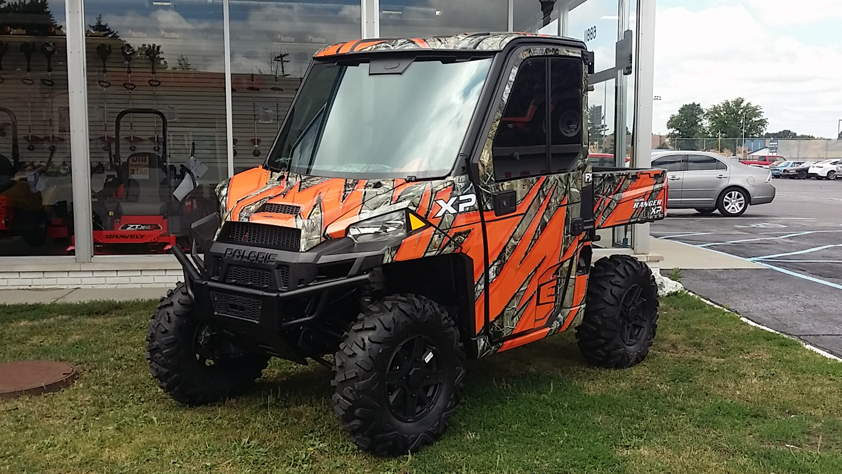 A Polaris Ranger 2 Door side-by-side with a orange and black real tree camo custom vinyl wrap.