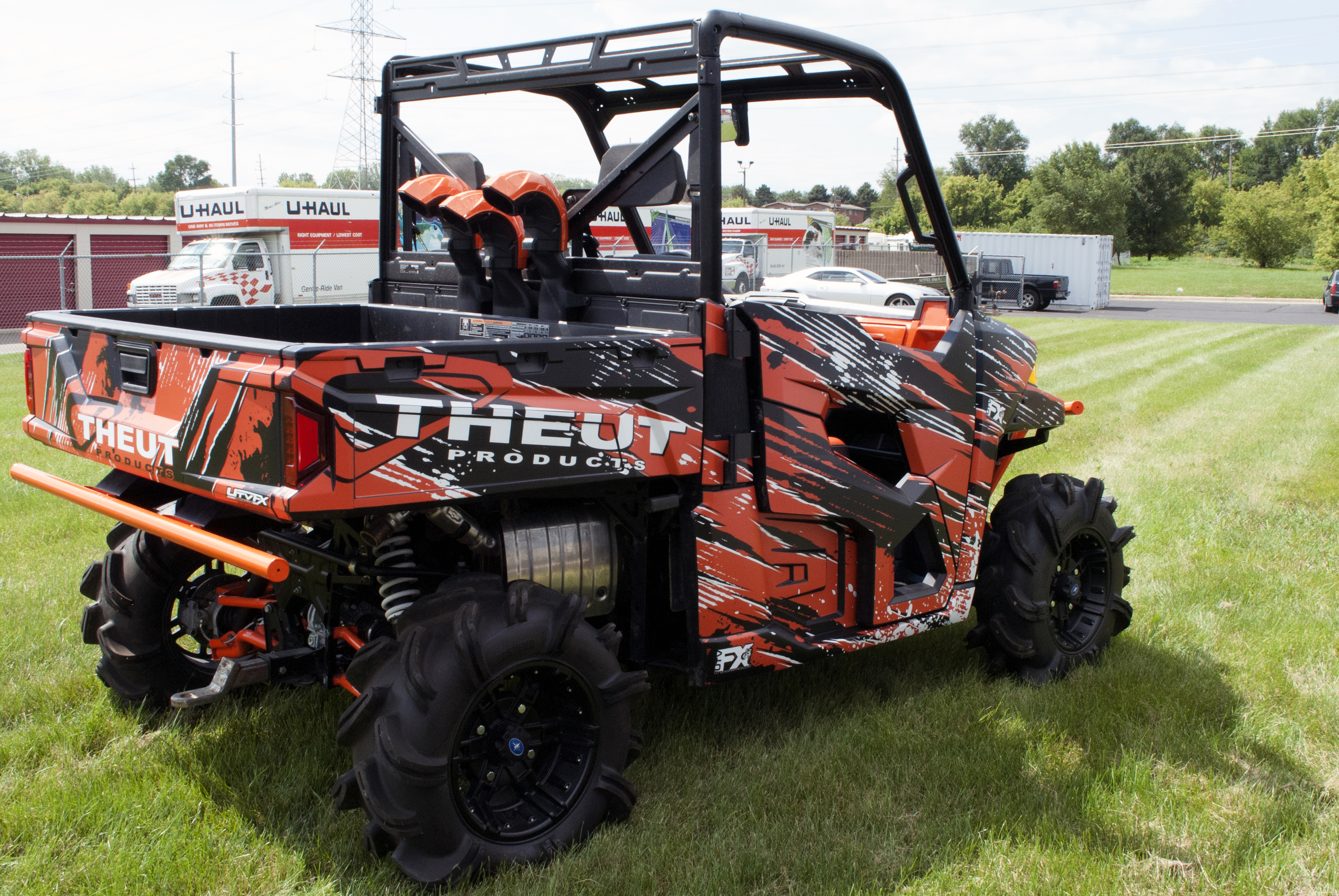 A Polaris Ranger 2 Door side-by-side with a black and orange Theut custom vinyl wrap.