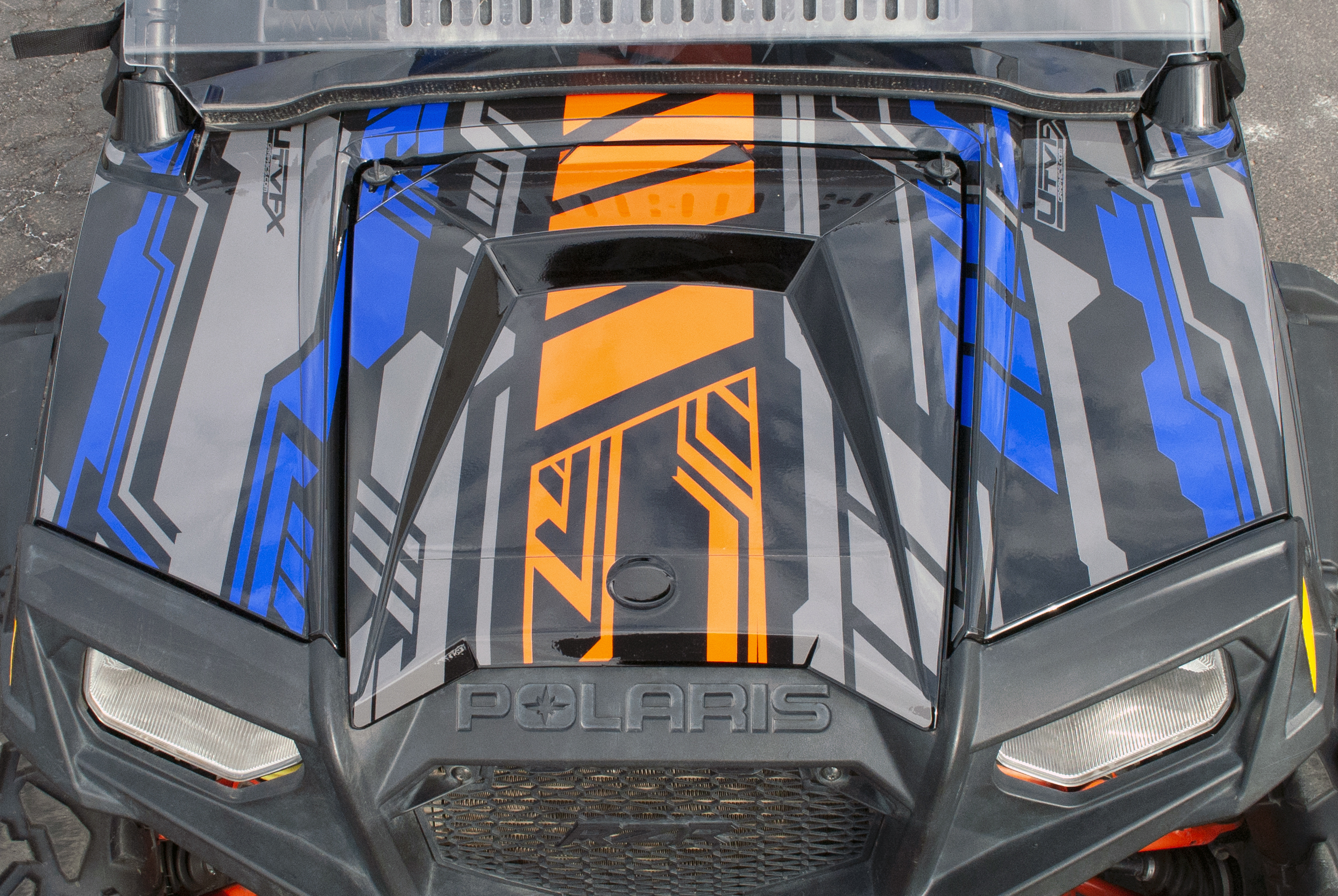 A Polaris RZR 2 Door side-by-side with a blue, black, and orange Evasion custom vinyl wrap.