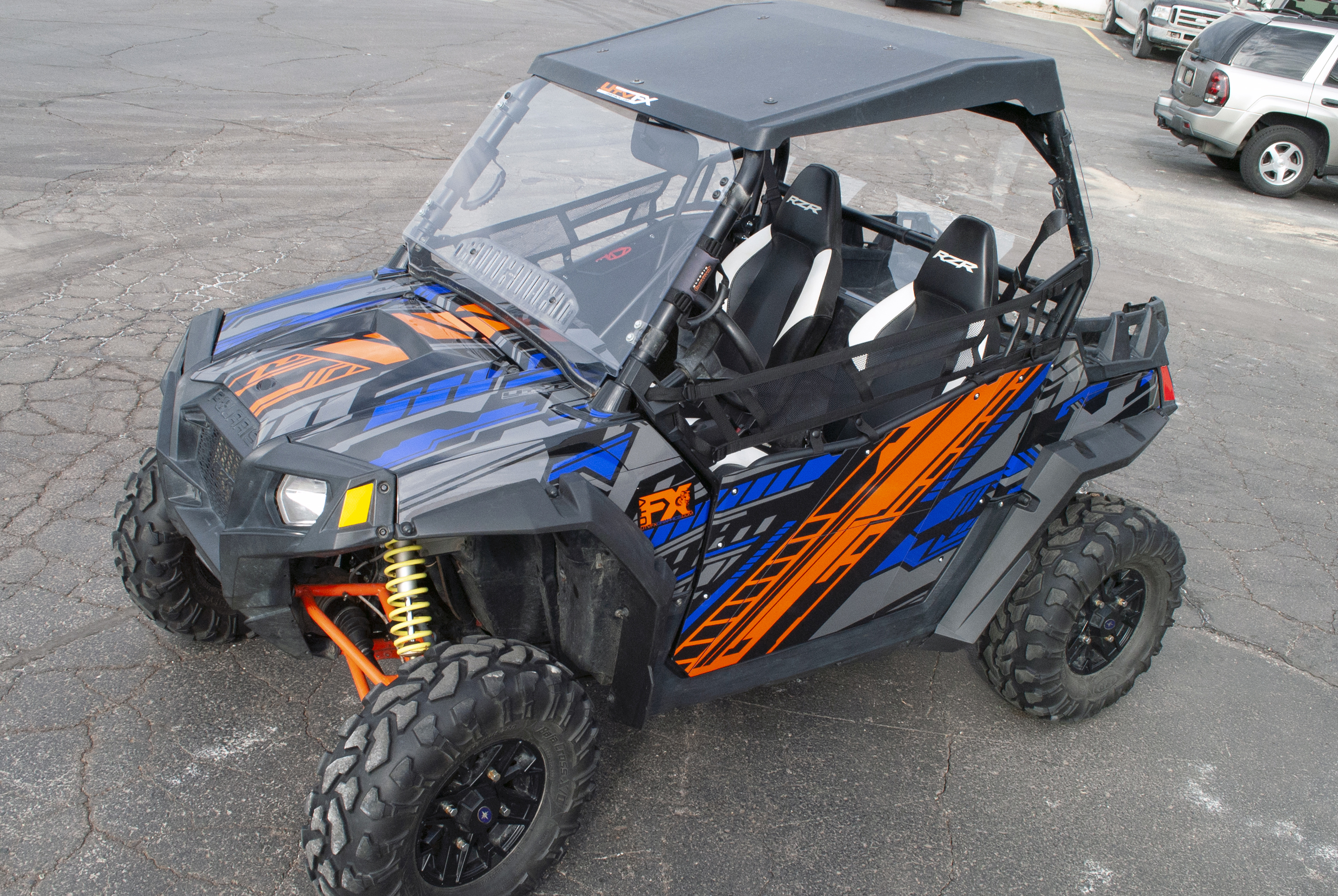 A Polaris RZR 2 Door side-by-side with a blue, black, and orange Evasion custom vinyl wrap.