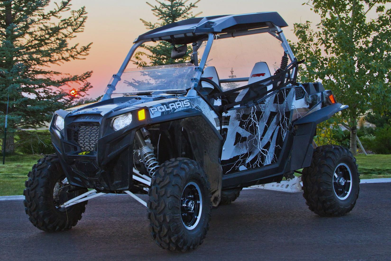 A Polaris RZR 2 Door side-by-side with a black and white Hard Rain custom vinyl wrap.