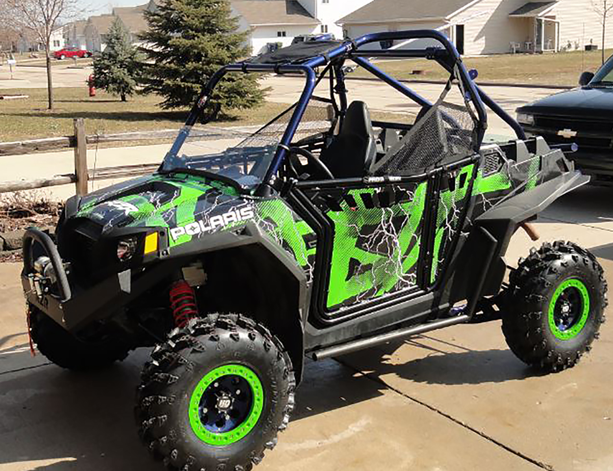A Polaris RZR 2 Door side-by-side with a black and green Hard Rain custom vinyl wrap.