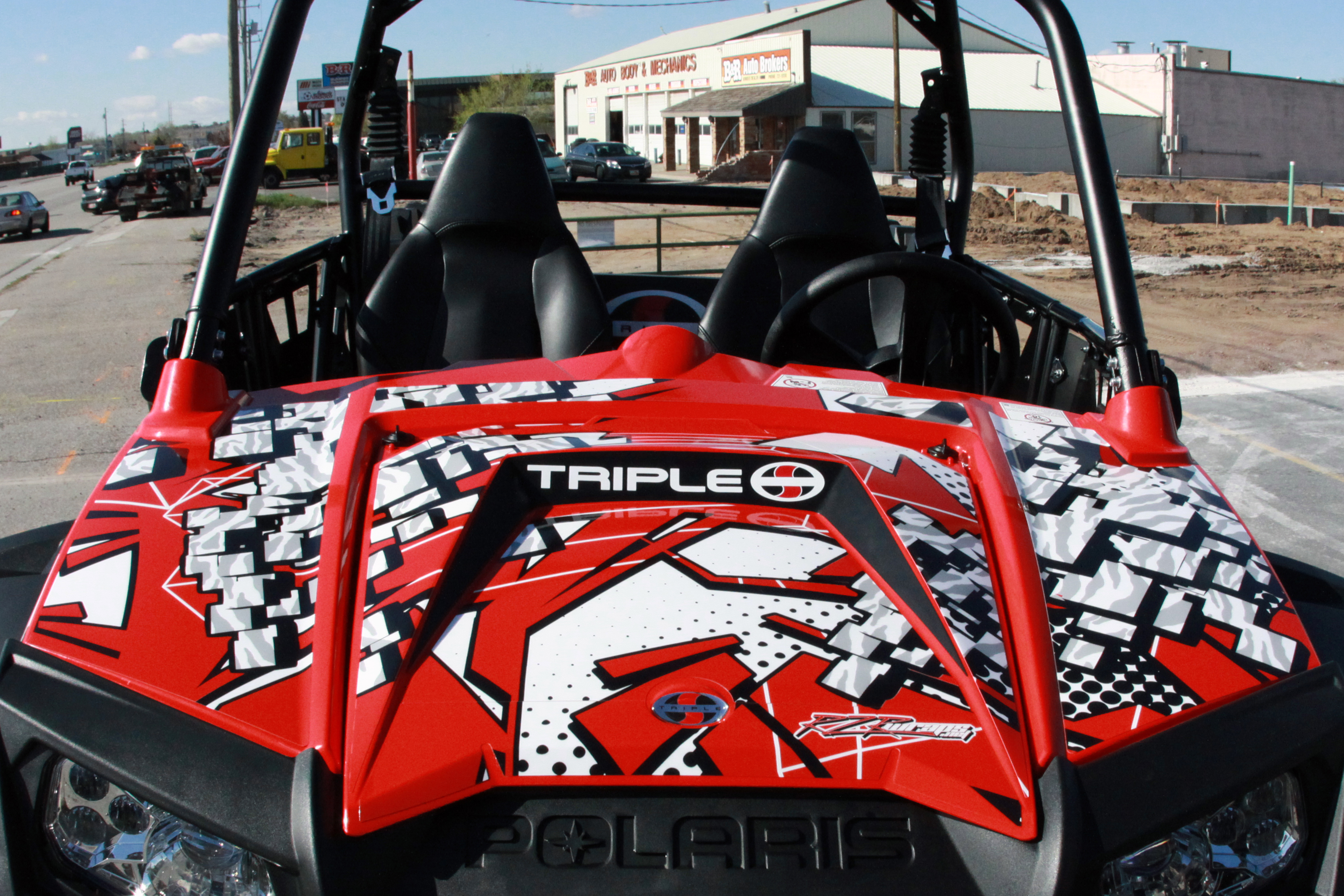 A Polaris RZR 2 Door side-by-side with a red and white Instinct custom vinyl wrap.