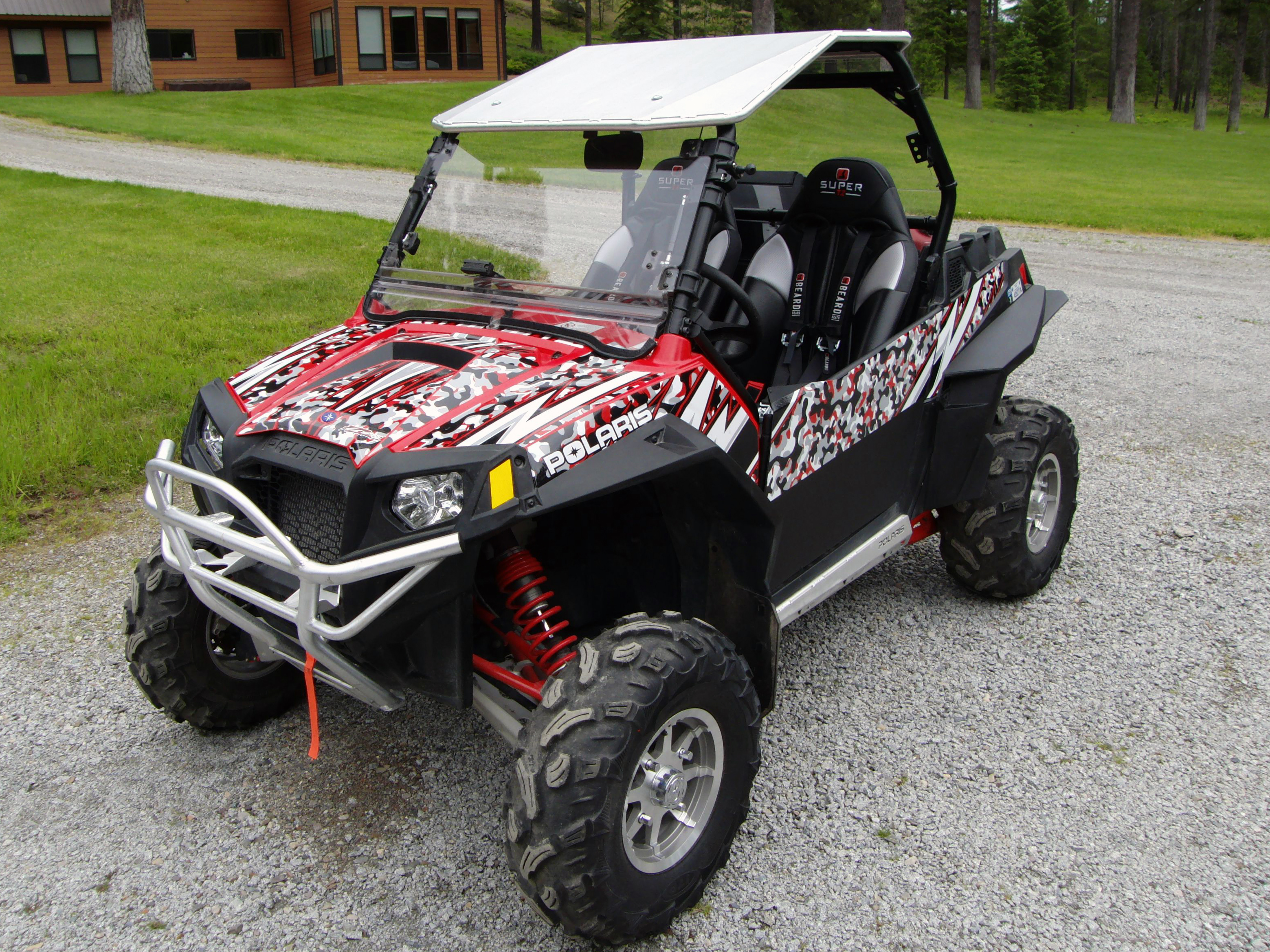 A Polaris RZR 2 Door side-by-side with a red and white snow camo custom vinyl wrap.