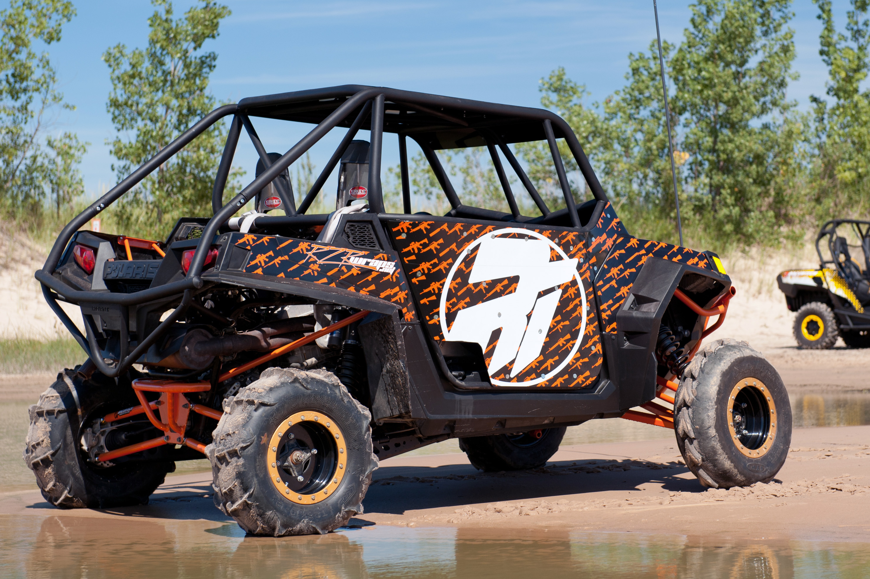 A Polaris RZR 2 Door side-by-side with a black and orange Underground custom vinyl wrap.