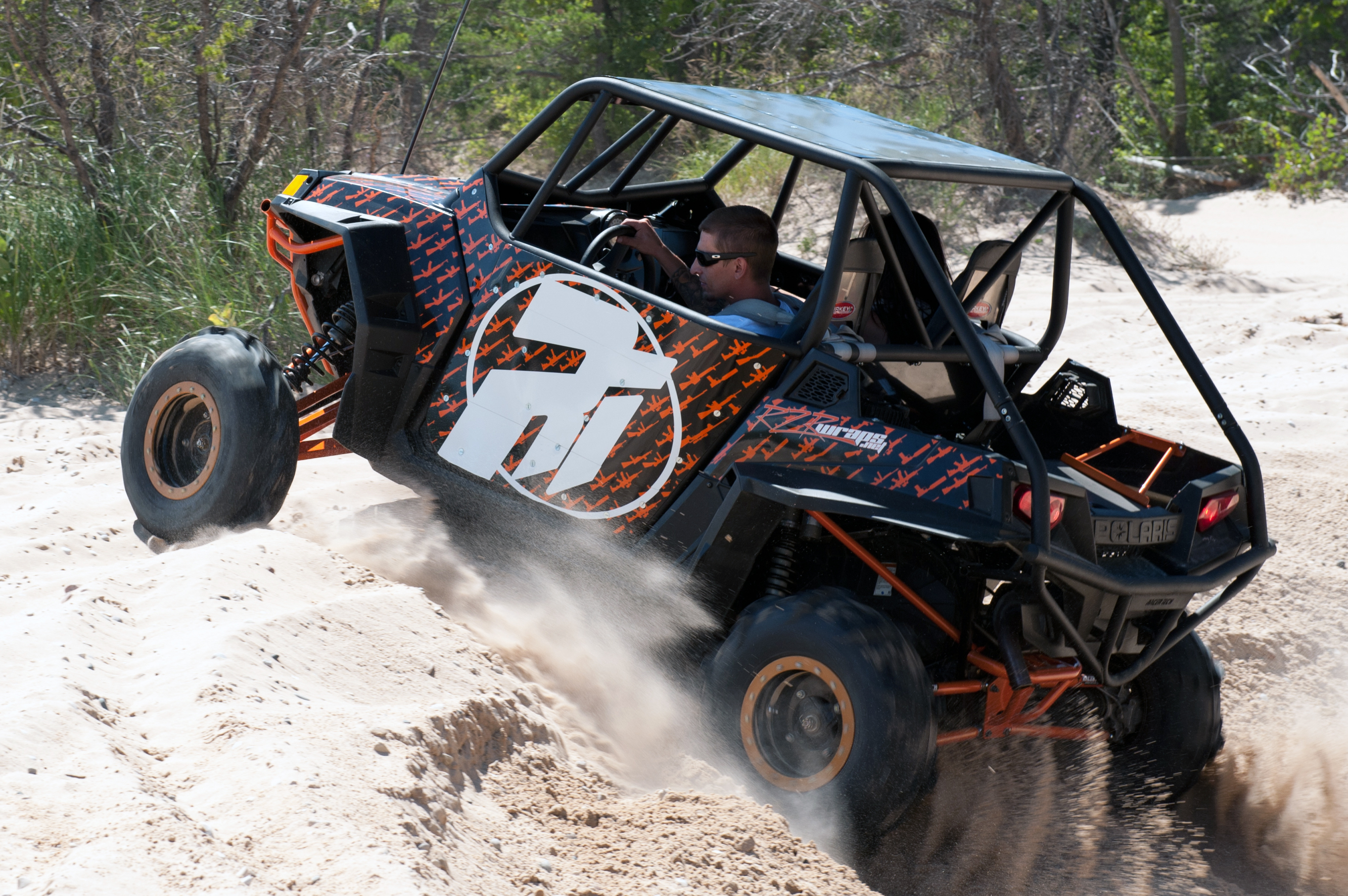 A Polaris RZR 2 Door side-by-side with a black and orange Underground custom vinyl wrap.