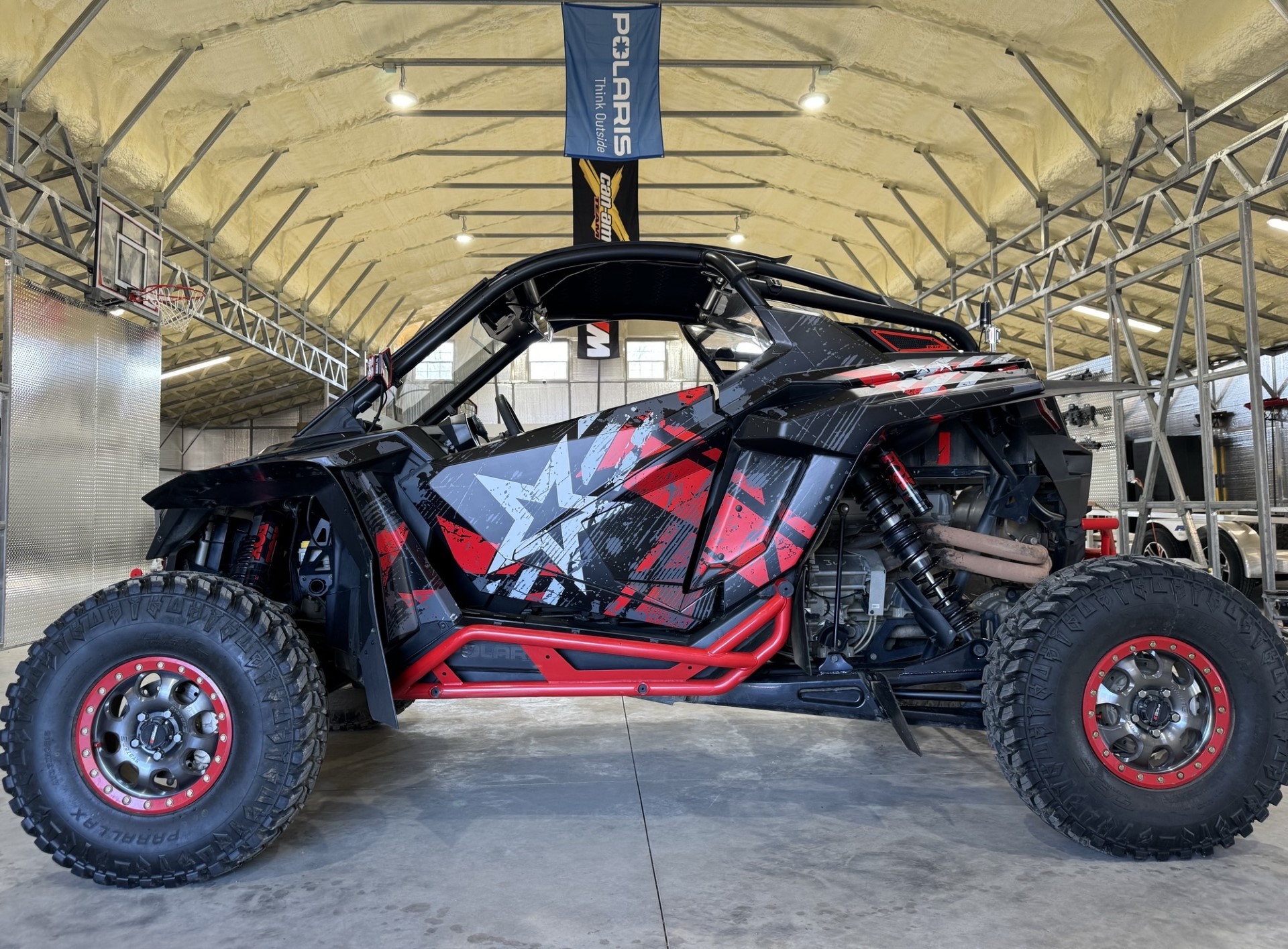 A Polaris RZR PRO R 2 Door side-by-side with a red, gray, and black grunge wartorn custom vinyl wrap.