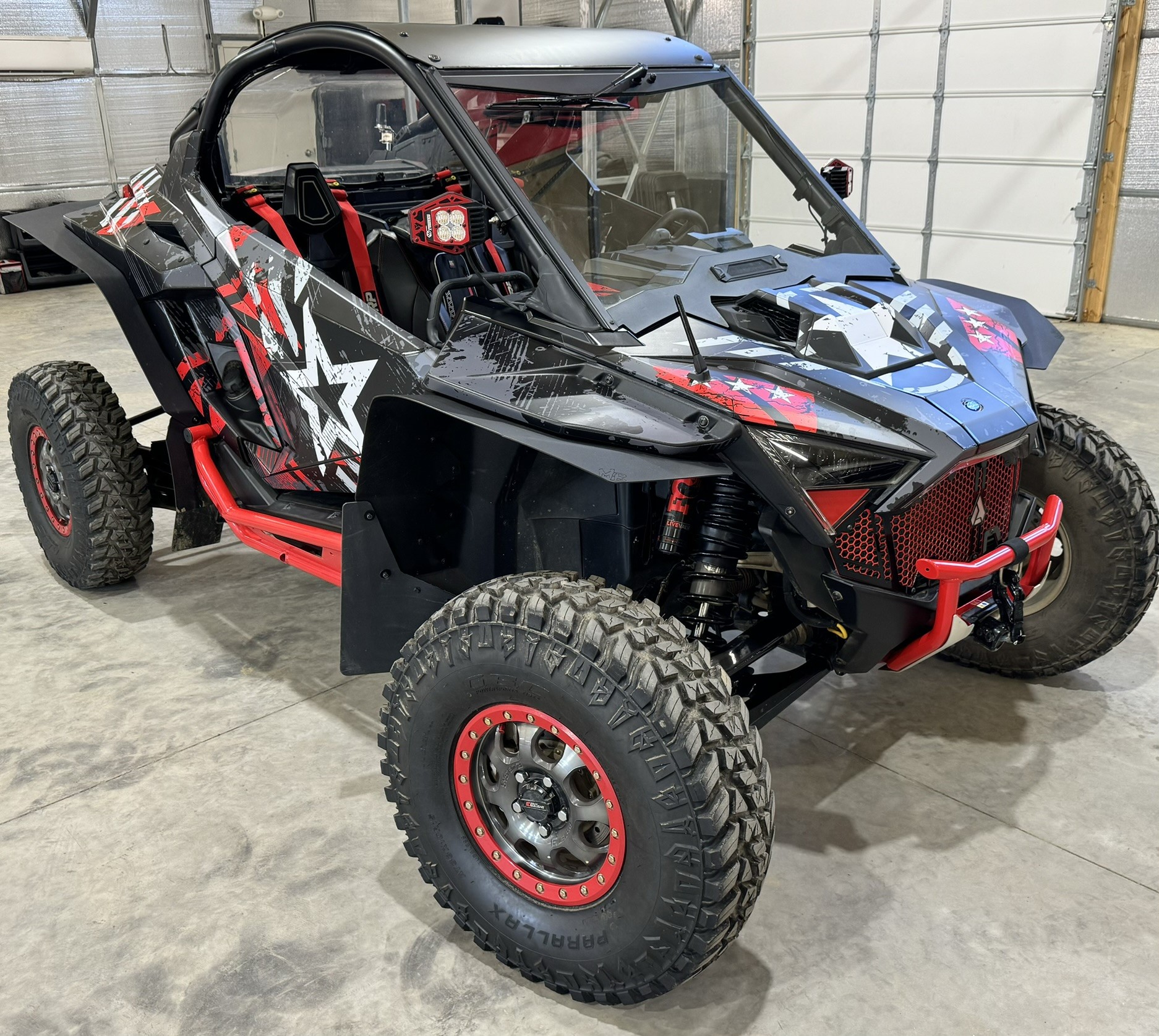 A Polaris RZR PRO R 2 Door side-by-side with a red, gray, and black grunge wartorn custom vinyl wrap.