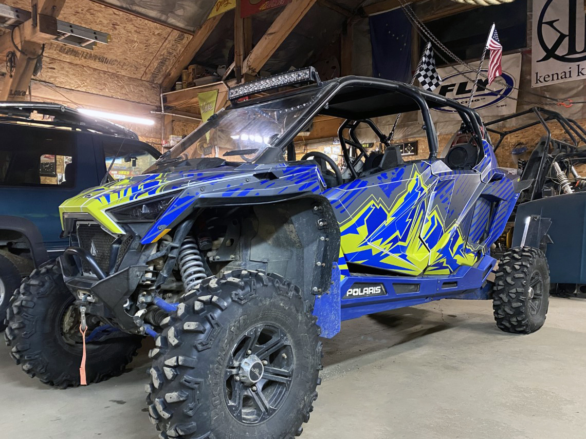 A Polaris RZR PRO XP 4 Door side-by-side with a lime squeeze, blue, and gray grunge mountain Altitude custom vinyl wrap.