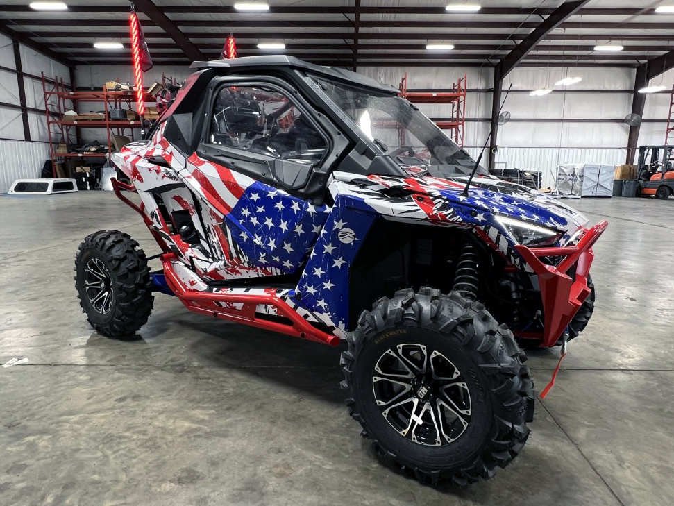 A Polaris RZR PRO XP 2 Door side-by-side with a red, white, and blue grunge American Flag custom vinyl wrap.