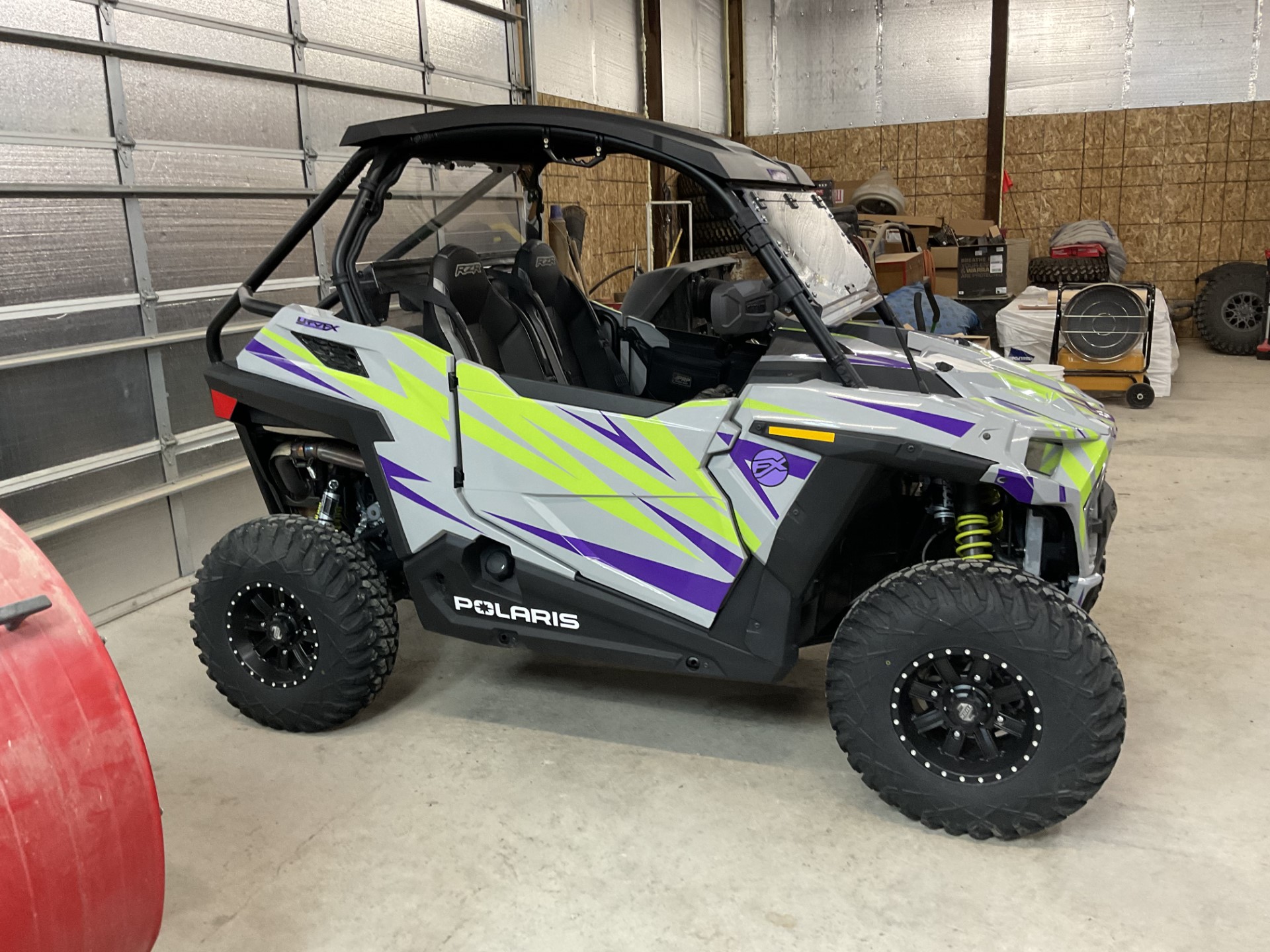 A Polaris RZR Trail 2 Door side-by-side with a gray, lime squeeze, and purple evolution custom vinyl wrap.
