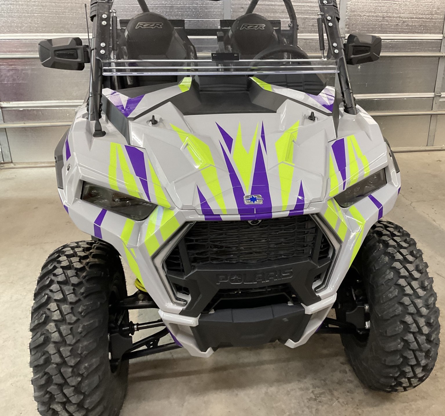 A Polaris RZR Trail 2 Door side-by-side with a gray, lime squeeze, and purple evolution custom vinyl wrap.