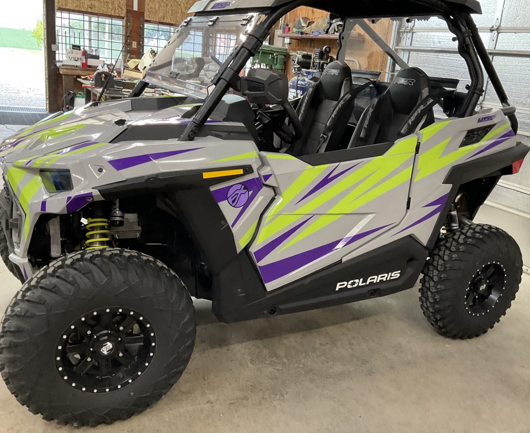 A Polaris RZR Trail 2 Door side-by-side with a gray, lime squeeze, and purple evolution custom vinyl wrap.