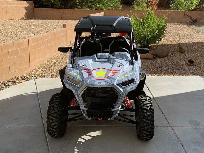 A Polaris RZR Trail 2 Door side-by-side with a gray, lime squeeze, and red grunge Wartorn custom vinyl wrap.