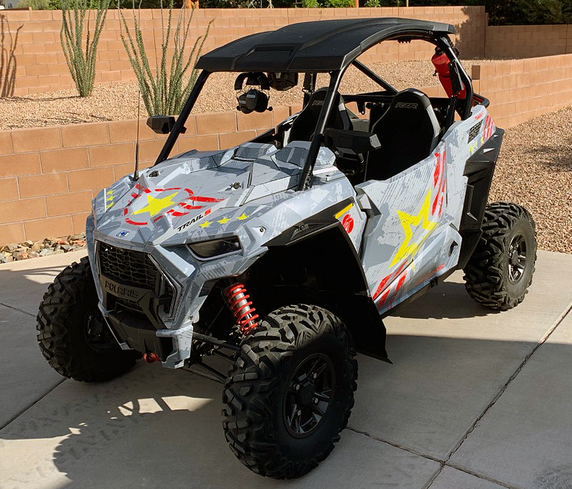 A Polaris RZR Trail 2 Door side-by-side with a gray, lime squeeze, and red grunge Wartorn custom vinyl wrap.