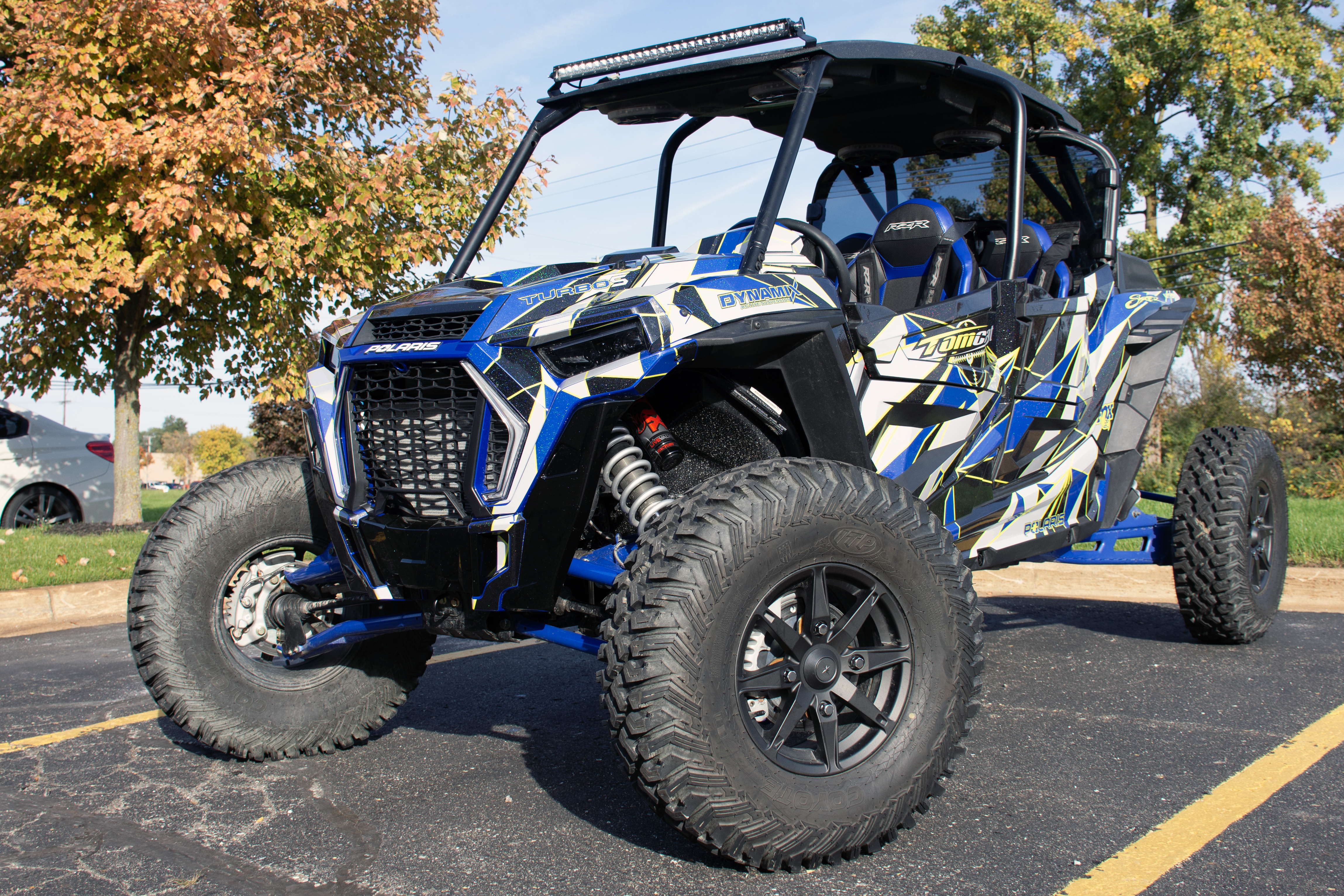 A Polaris RZR XP 4 Door 2018+ side-by-side with a lime squeeze, black, blue, and gray geometric triangle design Ascension custom vinyl wrap.