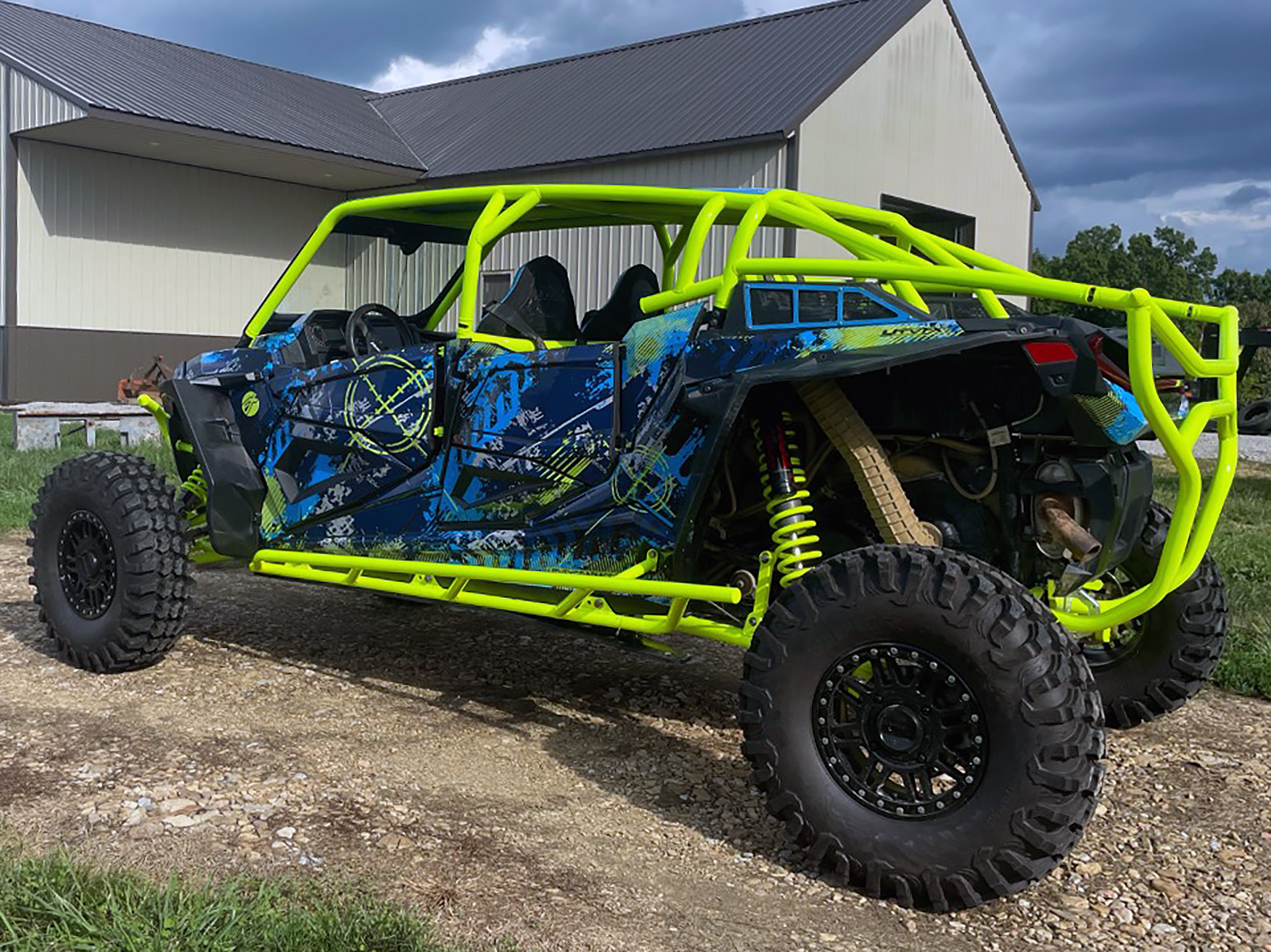 A Polaris RZR XP 4 Door 2018+ side-by-side with a black, lime squeeze, and blue grunge Bombsquad custom vinyl wrap.