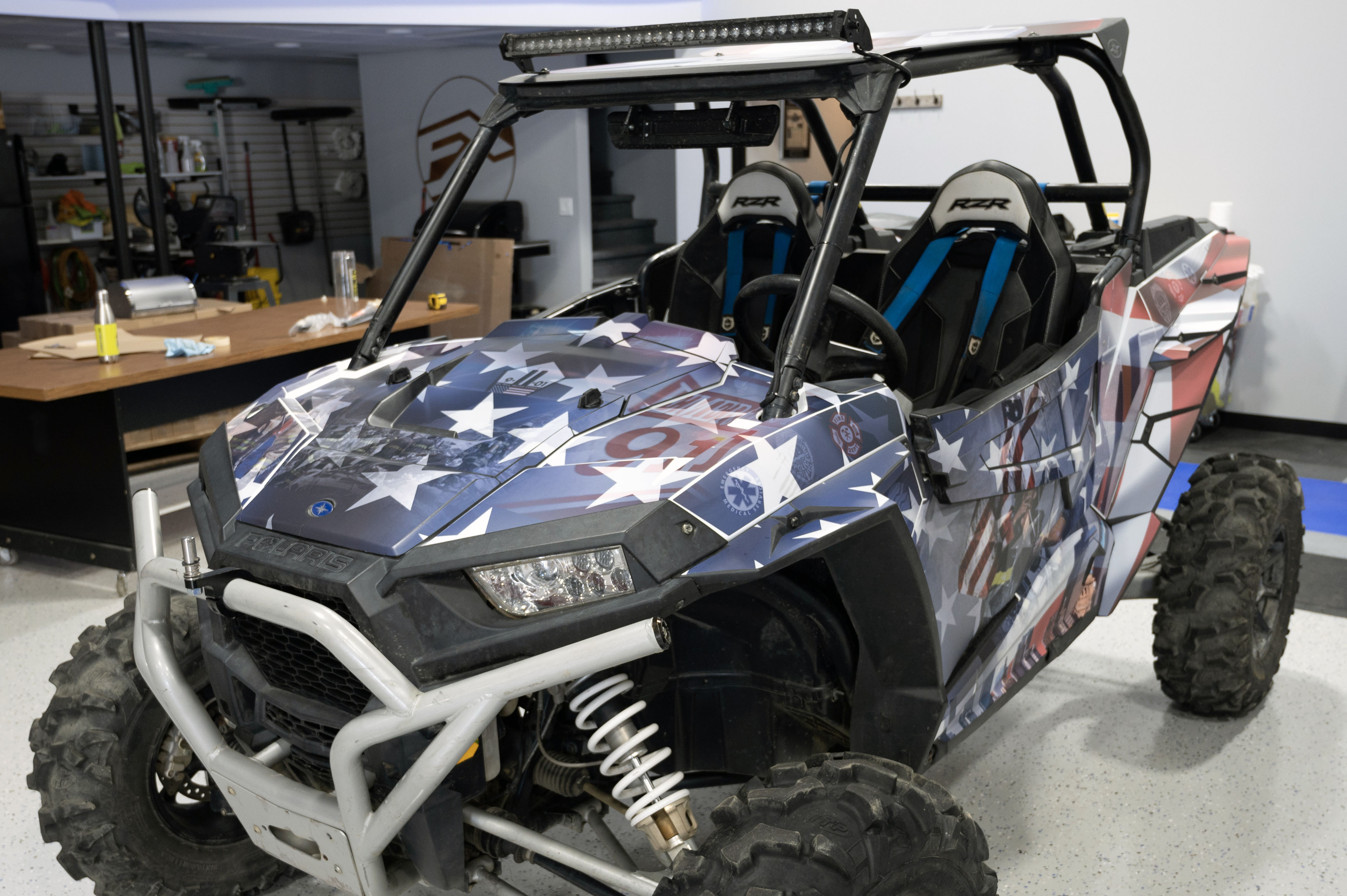 A Polaris RZR XP 2 Door side-by-side with a red, white, and blue American 911 Heroes custom vinyl wrap.