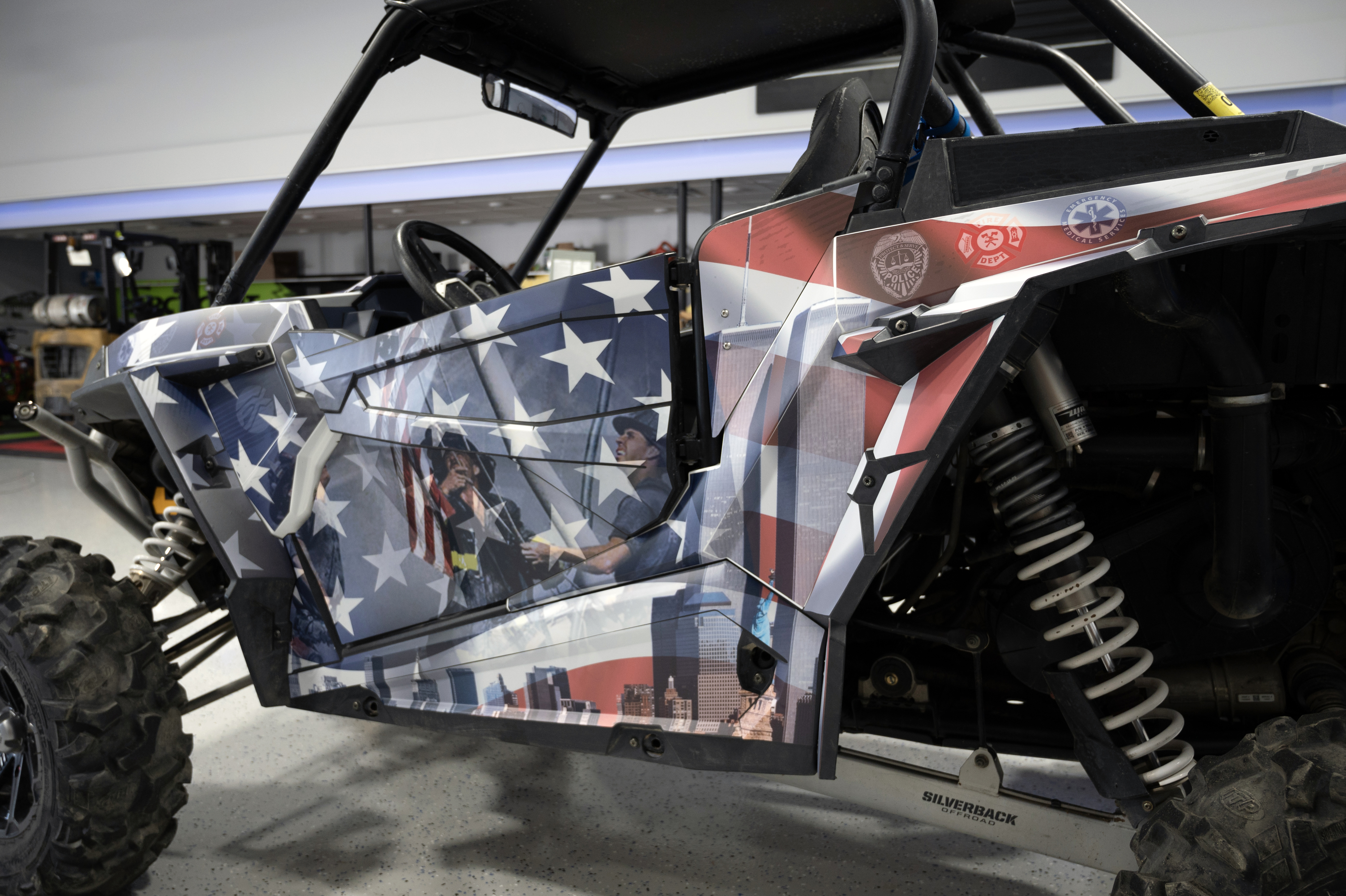 A Polaris RZR XP 2 Door side-by-side with a red, white, and blue American 911 Heroes custom vinyl wrap.