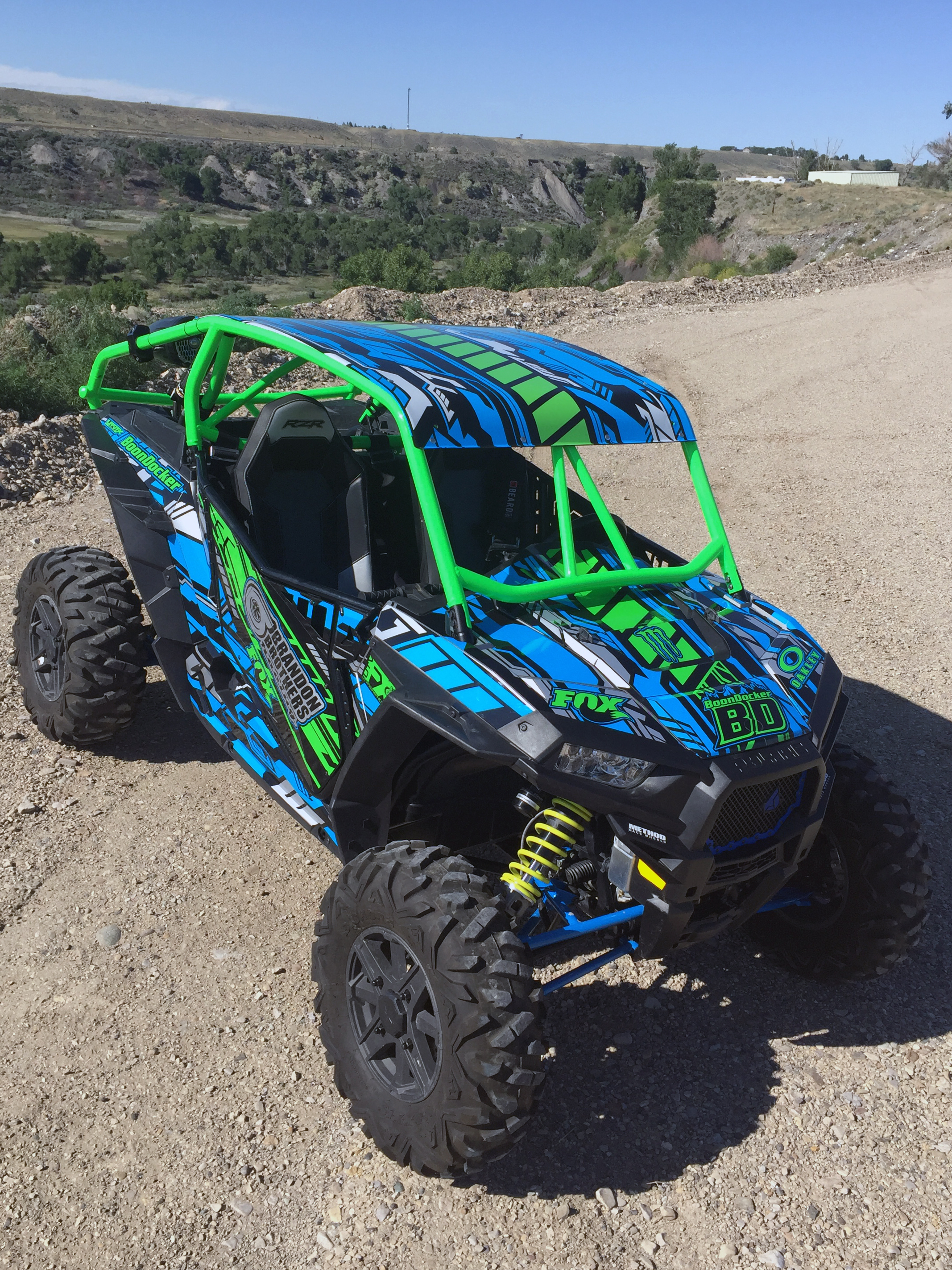A Polaris RZR XP 2 Door side-by-side with a blue, lime, and black stripes Evasion custom vinyl wrap. 