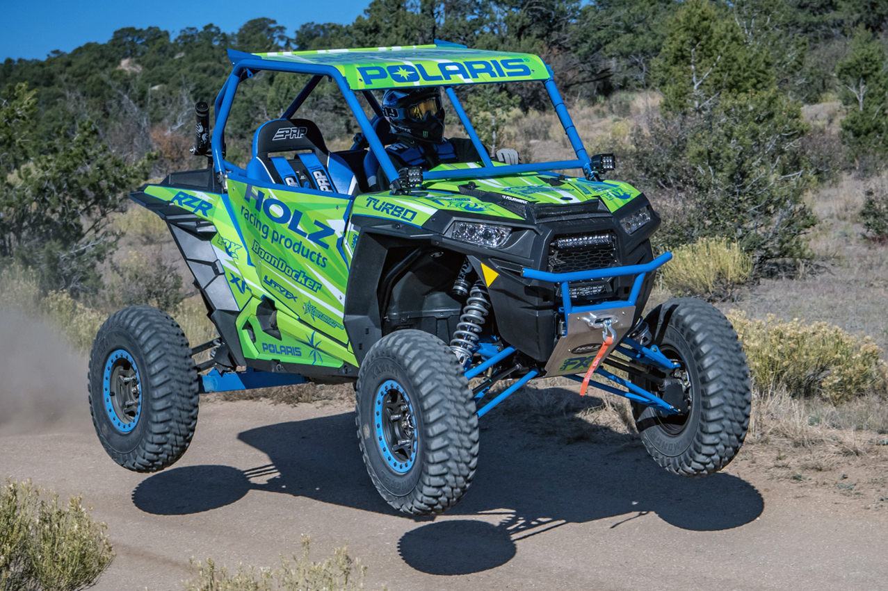 A Polaris RZR XP 2 Door side-by-side with a lime, blue, and white stripes Evolution custom vinyl wrap.